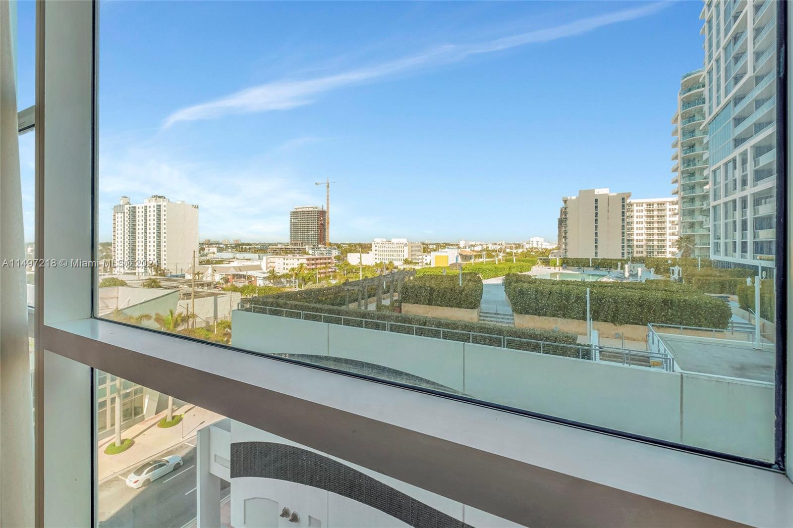 Green view of North Tower swimming pool deck from inside unit and skyline beyond.