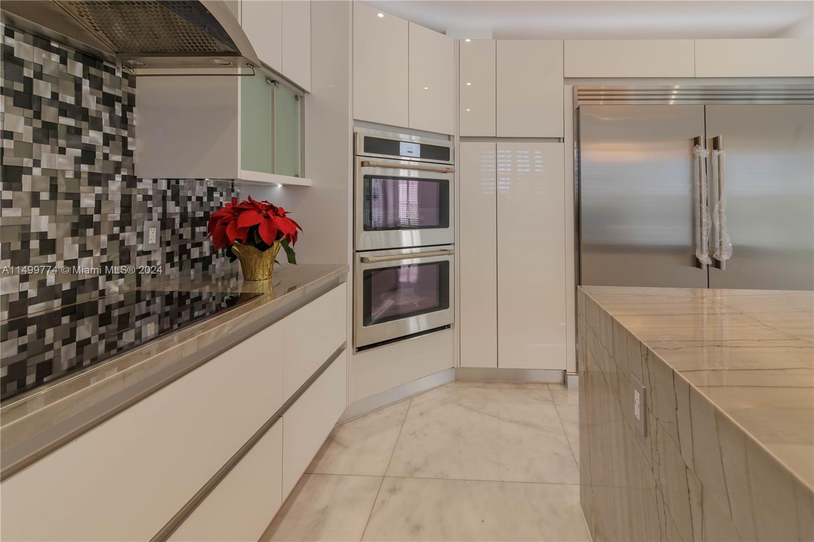 this designer kitchen with marble countertops, high-end stainless steel appliances, a marble island, and abundant storage space represents the perfect blend of style and functionality. It is a place where beauty and efficiency come together to create an exceptional culinary experience.