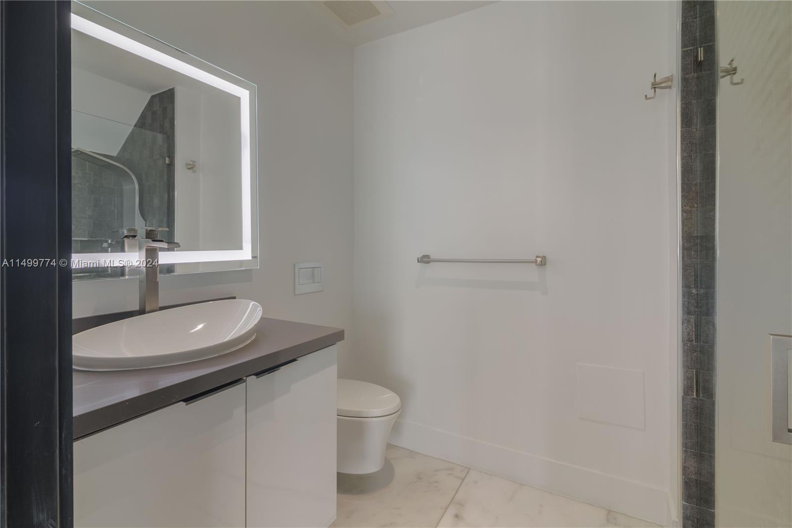 The full bathroom on the ground floor is a well-appointed and functional space that includes a vanity, a mirror, and a shower.