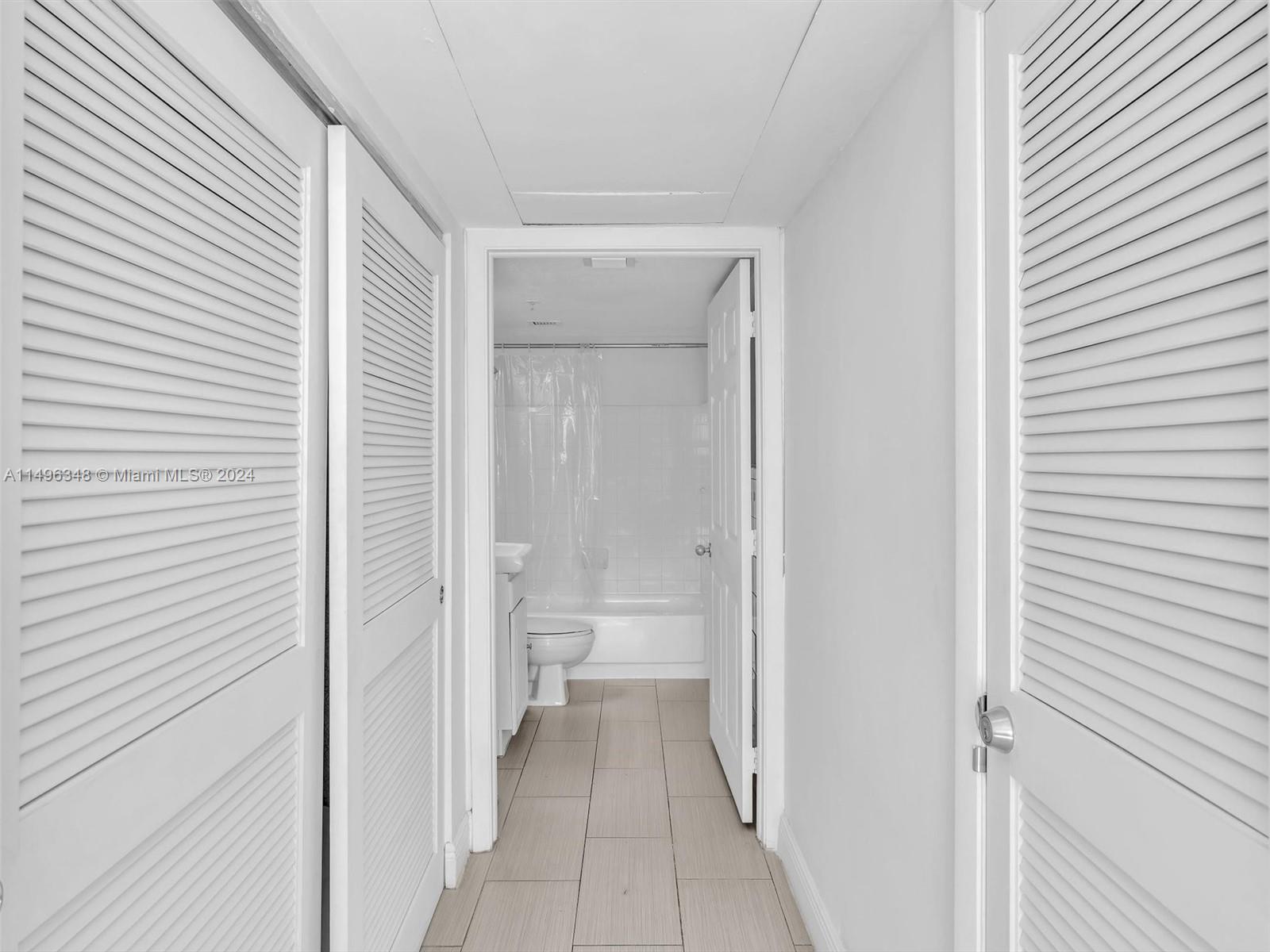 Hall of closets leading from primary bedroom to in-suite bath
