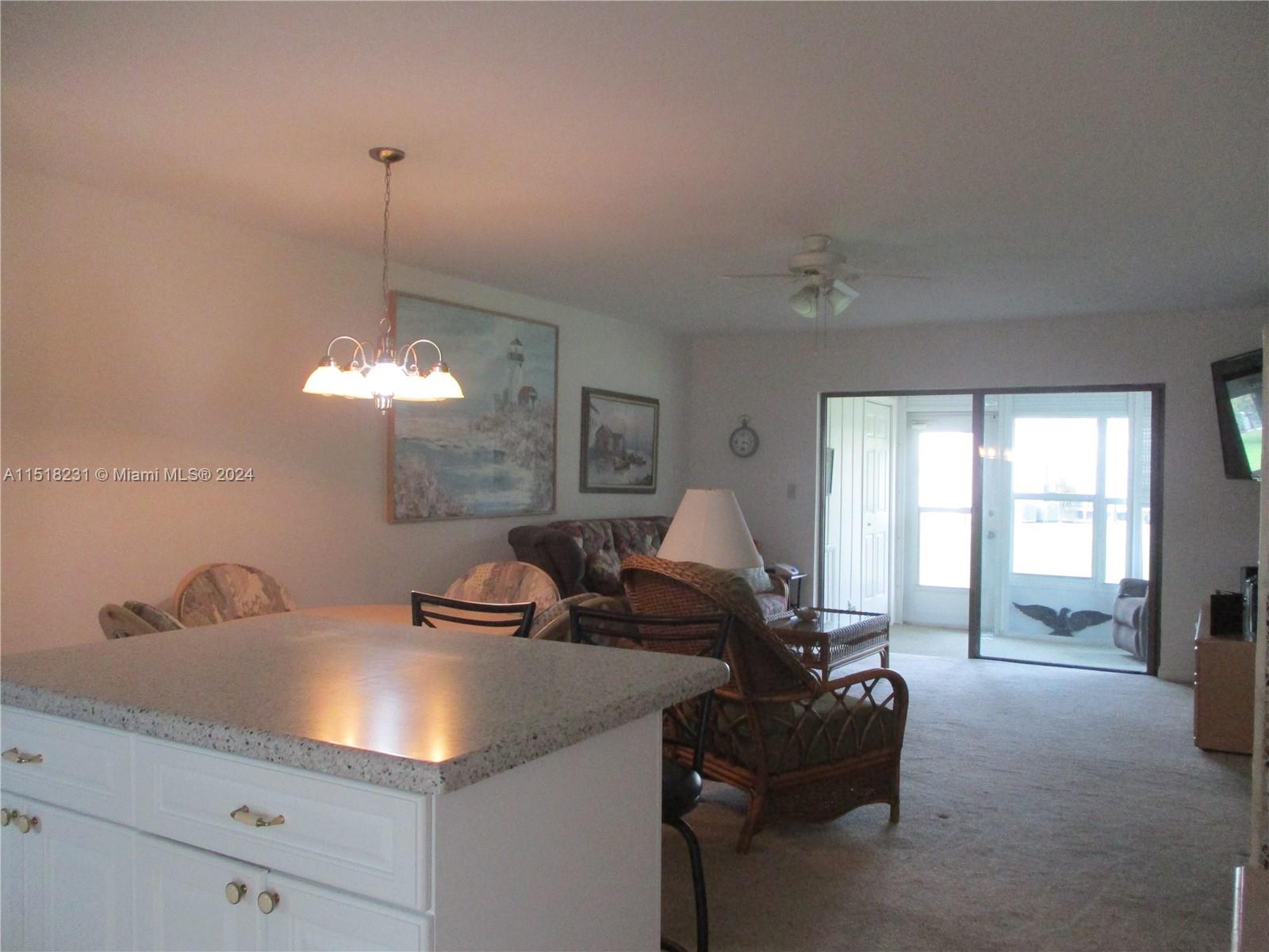 THE ISLAND, DINING AREA AND LIVING ROOM THAT FLOWS OUT INTO THE PATIO WITH THE GARDEN VIEW