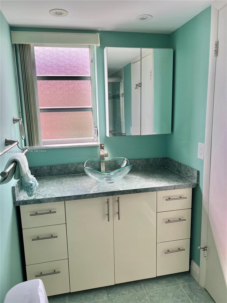 Updated primary ensuite with modern glass vessel sink & faucet, window, and plenty of countertop space & storage.