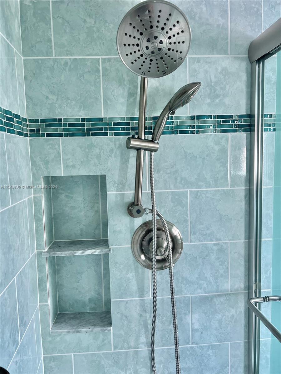 Primary bathroom featuring double shower heads (rain & hand-held) and double storage niches.