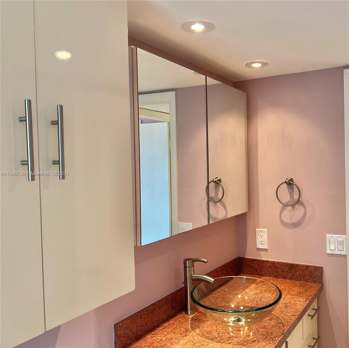 Guest bathroom features modern glass vessel sink & faucet, lots of countertop space and plenty of storage.