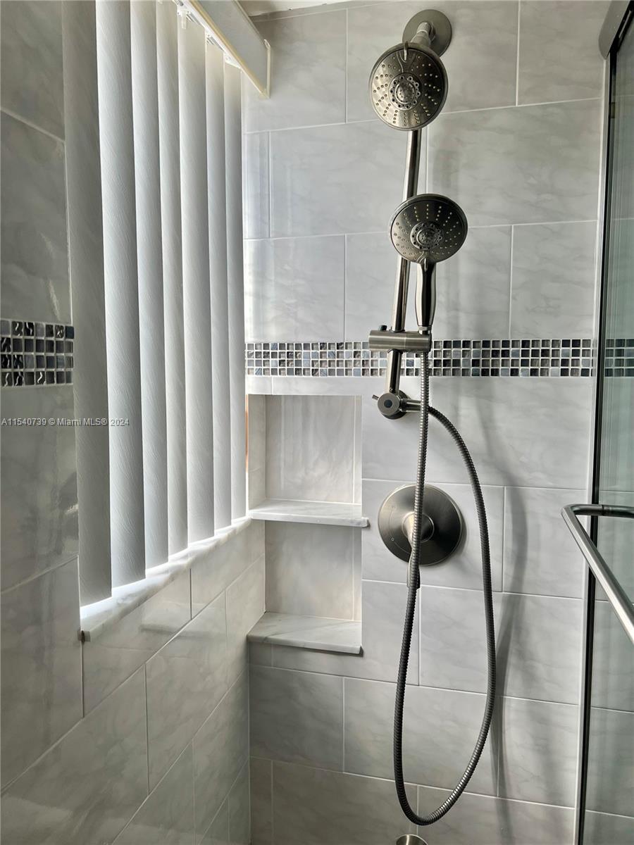 Guest bathroom features: window, modern shower tile with beautiful glass accent tile, double showerhead (rain & handheld) and 2 storage niches.