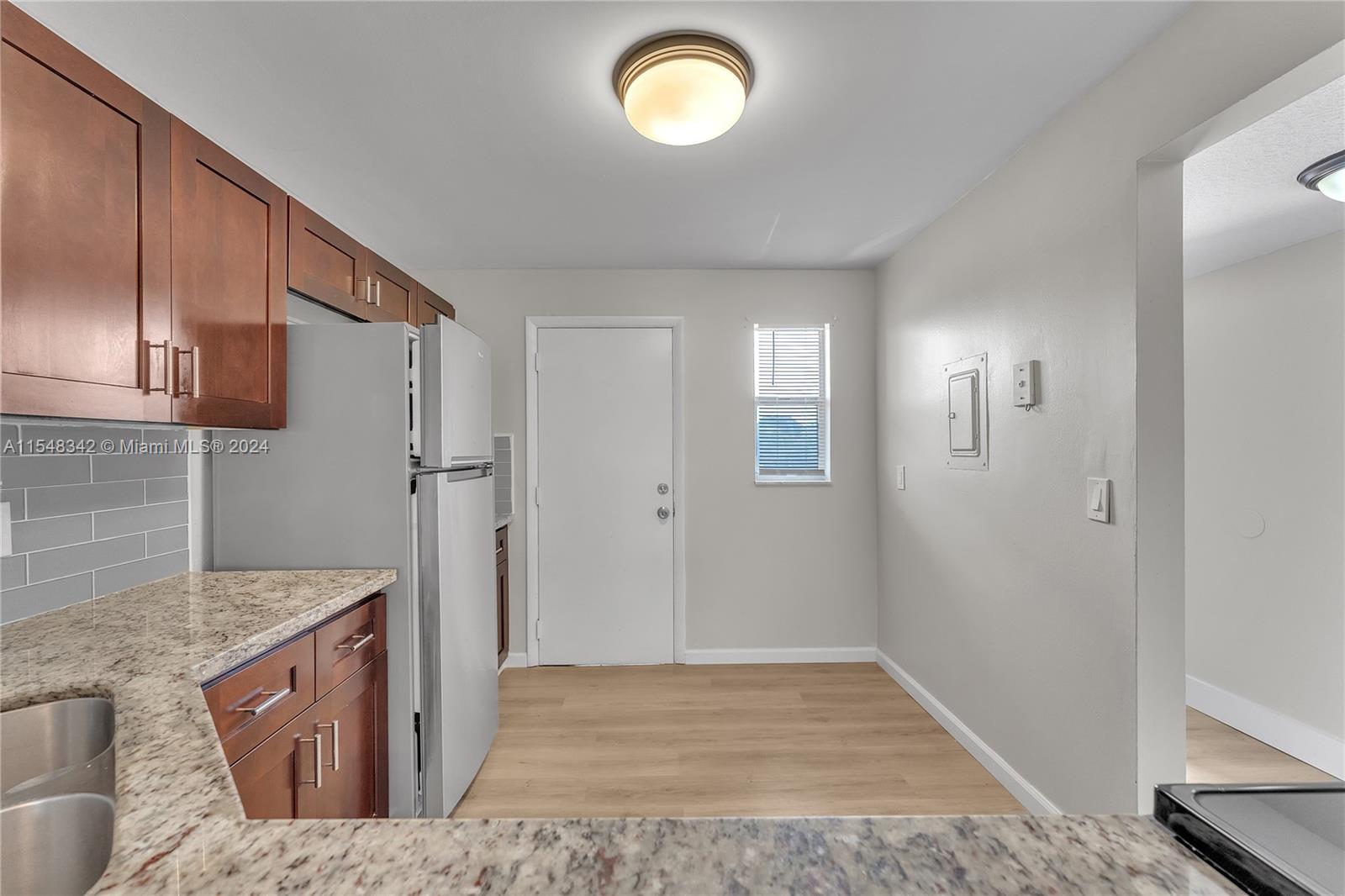 Partial View of Kitchen with View of Kitchen Door leading to Outdoor Corridor