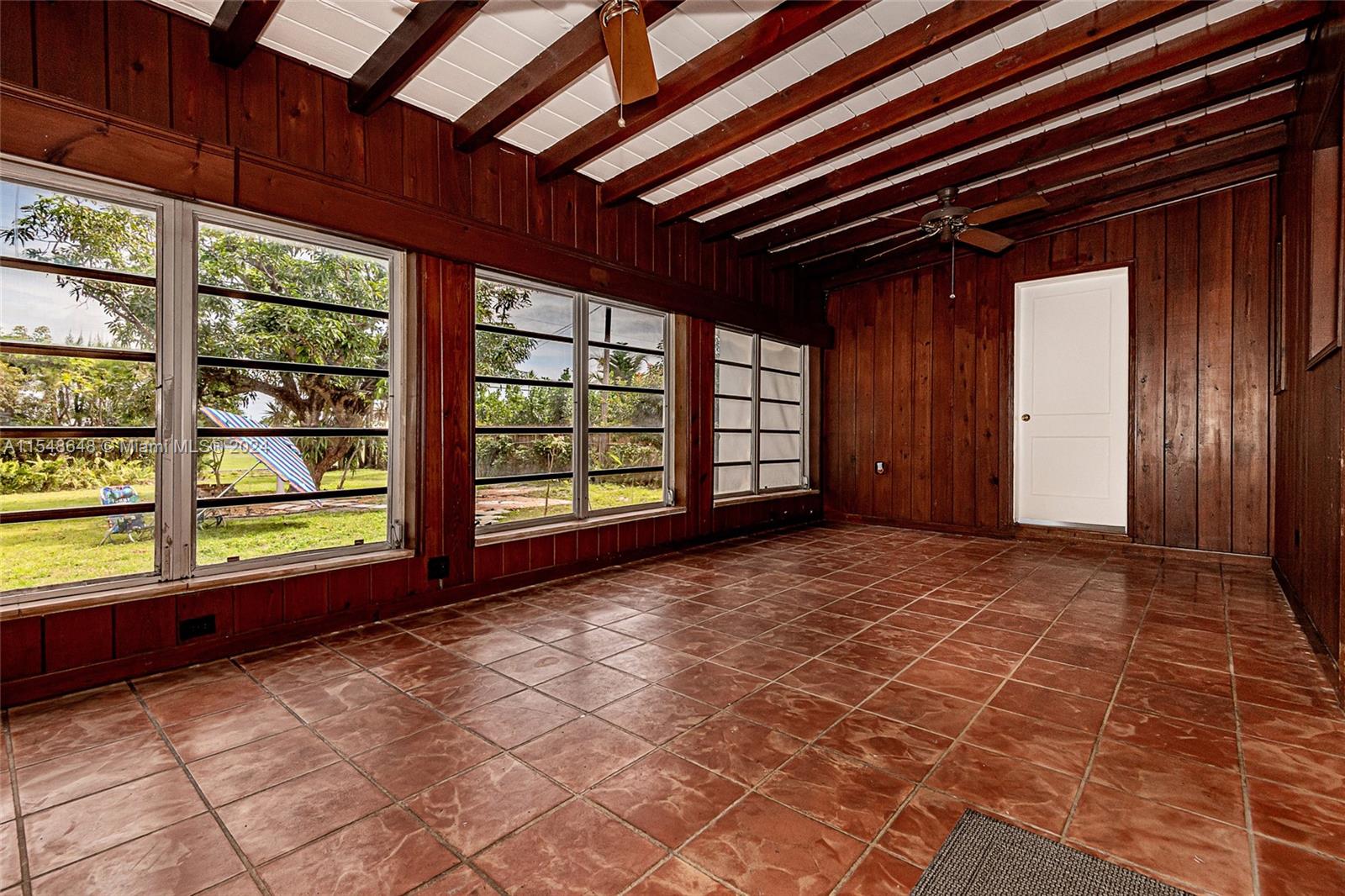 Florida Room with vintage, real wood paneling and fantastic views of the backyard. Door is to 1 of the bedrooms.