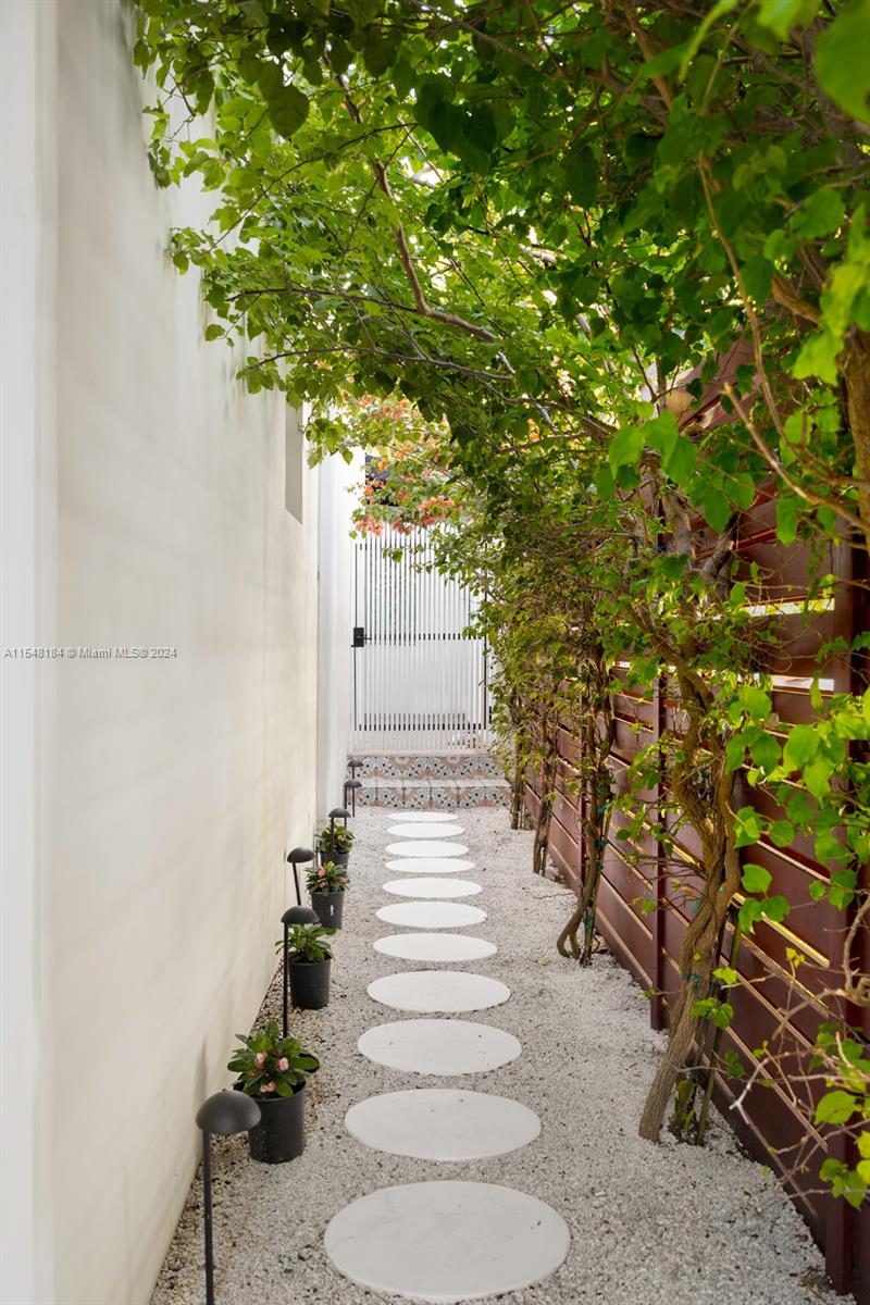 Beautiful back walkway with pebbles, stepping stones and tropical plants. View of the front side entrance gate.