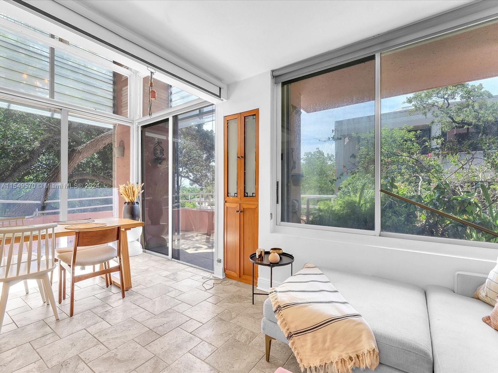 Living area and kitchen on the first floor open to a wrap-around balcony, providing abundant light and views of a lush landscape