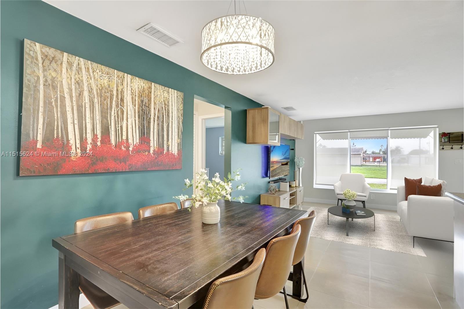 Step into this bright, open space where a rustic dining table, chic lighting, and a vibrant teal wall with abstract art create a modern, welcoming vibe, perfect for lively gatherings or tranquil moments. Photo, virtually staged.