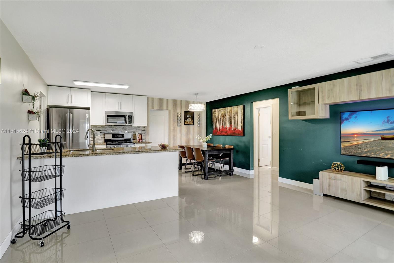 Modern meets classic in this airy kitchen with sleek appliances, opening to a cozy dining nook bathed in warm light, all accented by eclectic wall art and a touch of greenery for a homely, stylish vibe.