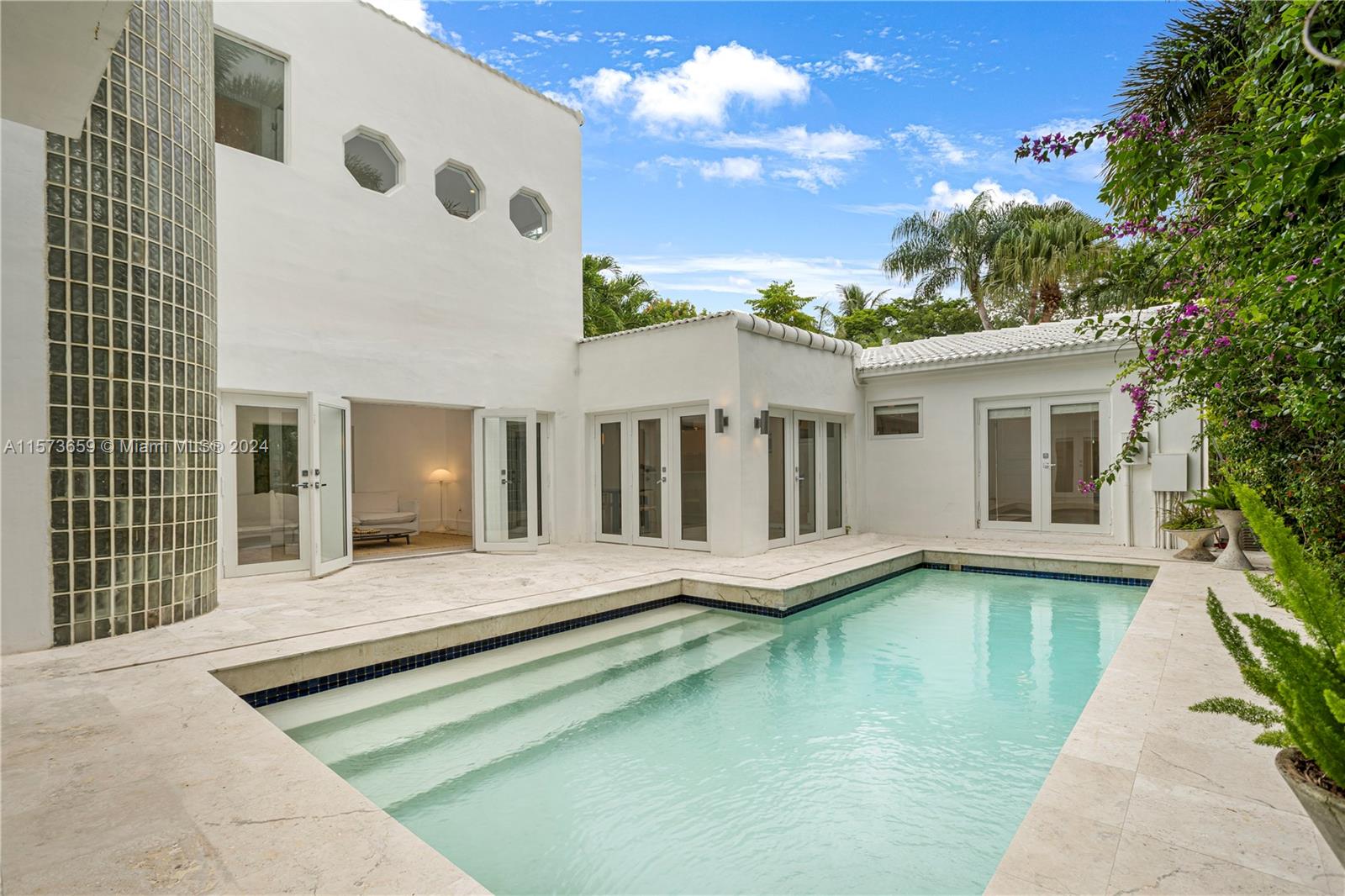 Multilevel home with St Barts villa vibes in a serene Coconut Grove location. Boho-chic design details abound in the airy layout featuring stark white interiors, light oak floors, glass block walls, porthole windows, high ceilings and a stunning spiral staircase. Upstairs suite enjoys a pool view from a Juliette balcony and a large sitting room with fireplace. Spacious open-plan living/dining/family area has a whitewashed vaulted ceiling and wide glass doors opening to a magnificent pool and lush tropical garden, perfect for indoor/outdoor entertaining. The compound is completely gated with ample parking for up to five cars. Stroll to pristine nature preserves and Biscayne Bay. Less than a mile from top schools and the Grove’s trendy shopping & dining options.