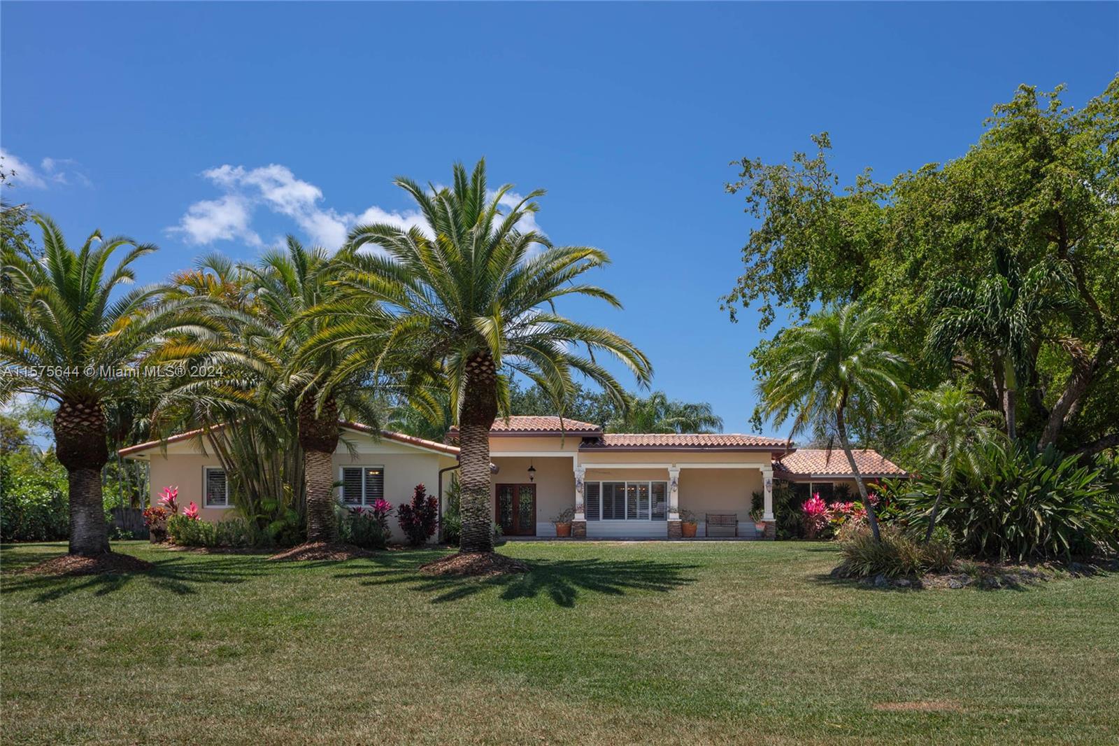 In the Northeast corner of Palmetto Bay sits this sprawling and tropical compound. On over 30,000 square feet at the corner of two cul-de-sacs, you’ll find everything your family could need or want. This home is waiting to entertain with well-appointed chef’s kitchen with gas range and large breakfast area, formal living/dining room with French doors to the freeform pool, deck, and L-shaped tiki hut, oversized family room, and private in-law’s quarters. Standalone three-car garage can accommodate your cars and boat or be partially converted into a guest house with nearby plumbing and electric. Stone and hardwood floors, impact windows/doors, and plantation shutters throughout. Walking distance to top private and public schools and the 50-acre Coral Reef Park. Some photos virtually staged.