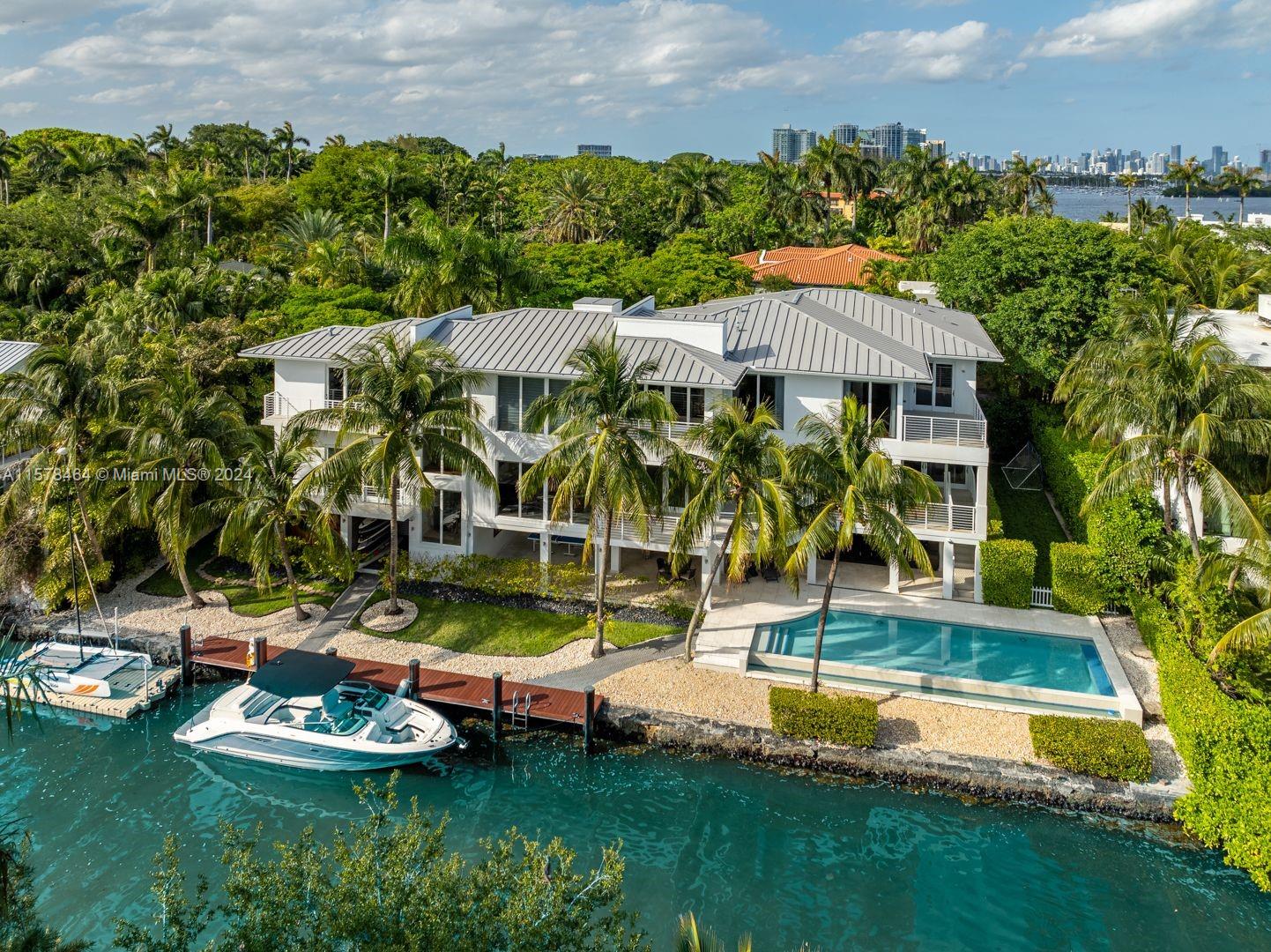 Breathtaking 11,316 SF waterfront home in Four Way Lodge Estates,  a highly sought-after gated community in Coconut Grove. with 6 bedrooms, 6 bathrooms and 2 half-bathrooms. Voluminous ceilings and a light-filled open floor plan provide for beautiful water views. The  gourmet kitchen includes an expansive island, gas stove, and premium appliances, and a covered terrace has a fully equipped summer kitchen and play area with turf. The estate offers 150 ft of water frontage and easy access to Biscayne Bay. A stunning infinity saltwater pool overlooks the waterway, and a floating dock tied to a lighted seawall area accommodates boats of various sizes.  Other features include an elevator, whole house generator, impact windows and doors, 2-car garage, and 3 carports.