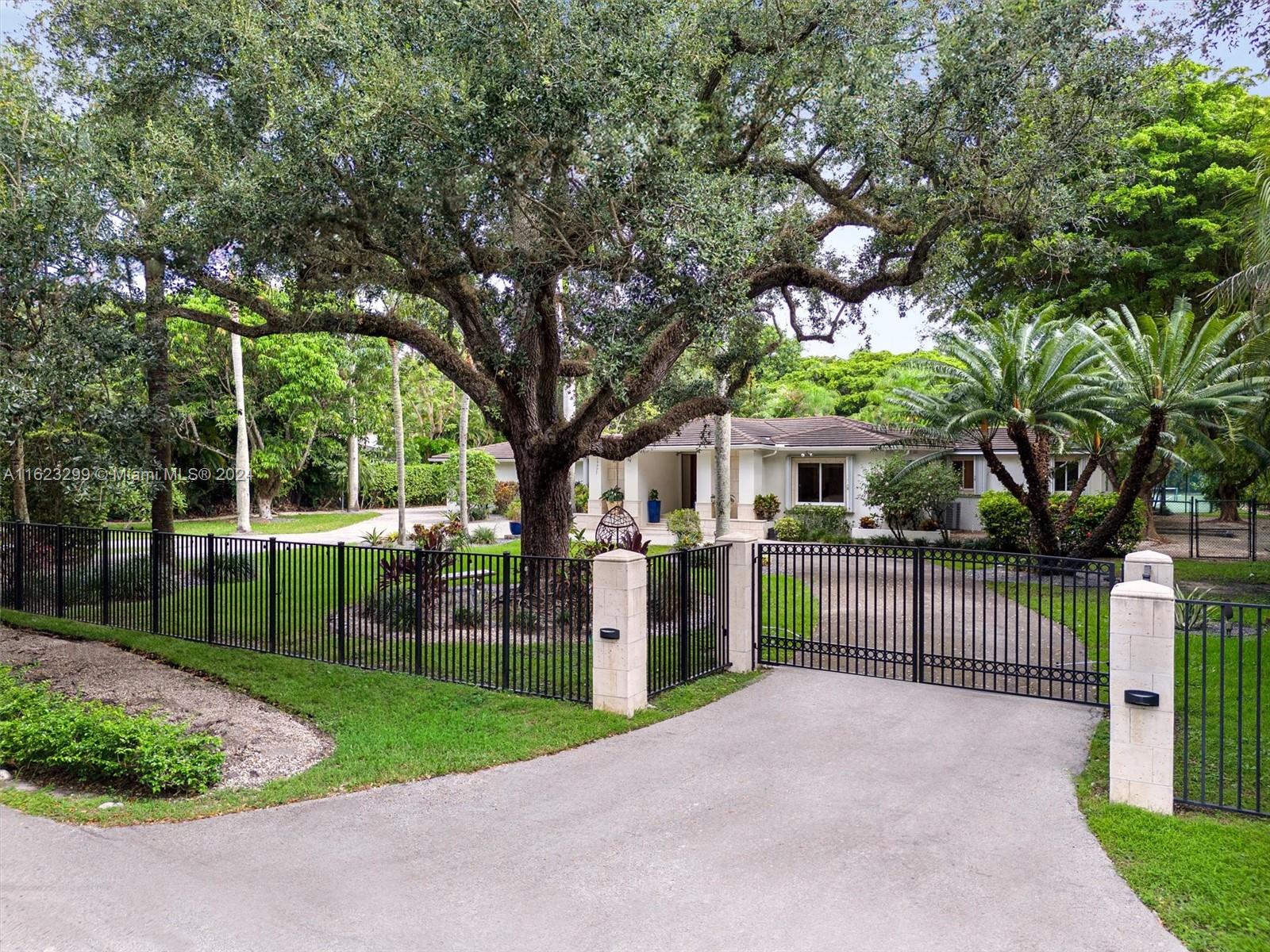 Welcome to your private oasis in North Pinecrest! This stunning one-story gated retreat spans 7,476 total sq. ft. on a lushly landscaped 50,529 sq. ft. lot, blending luxury and tranquility. The spacious 4BR/3BA main house boasts a new gourmet kitchen with Viking appliances, living room, dining room, family room, home office, and media room. Other amenities include a 1BR/1BA guest house & fitness studio w/ half bath. The expansive backyard is an entertainer's paradise, with a sparkling pool, Jacuzzi, and summer kitchen. Enjoy the lighted north/south tennis court, relax in the tiki hut, or stroll the nature trail. Additional features include a newer roof, whole-house generator, hurricane protection, 2-car garage, and 2-car carport. Experience the ultimate in luxury in your private sanctuary.