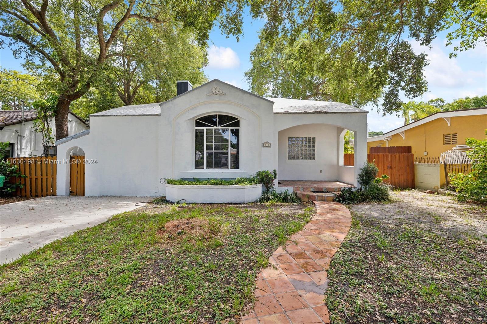 This charming 2-bedroom, 2-bathroom home located in the desirable The Roads. Built in 1938, this one-story residence exudes vintage charm with its original hardwood floors and classic tile throughout, offering a warm and inviting atmosphere reminiscent of a bygone era.
As you enter, you'll be welcomed by high ceilings in the living room, filled with natural light and centered around a cozy fireplace. The home features a family room and a versatile den/office room, perfect for working from home or creating your own personal retreat. The den/office room boasts an abundance of natural light and overlooks the serene backyard. The fenced-in backyard is a gardener's paradise, shaded by mature fruit trees and adorned with unique staghorn ferns hanging from the branches.