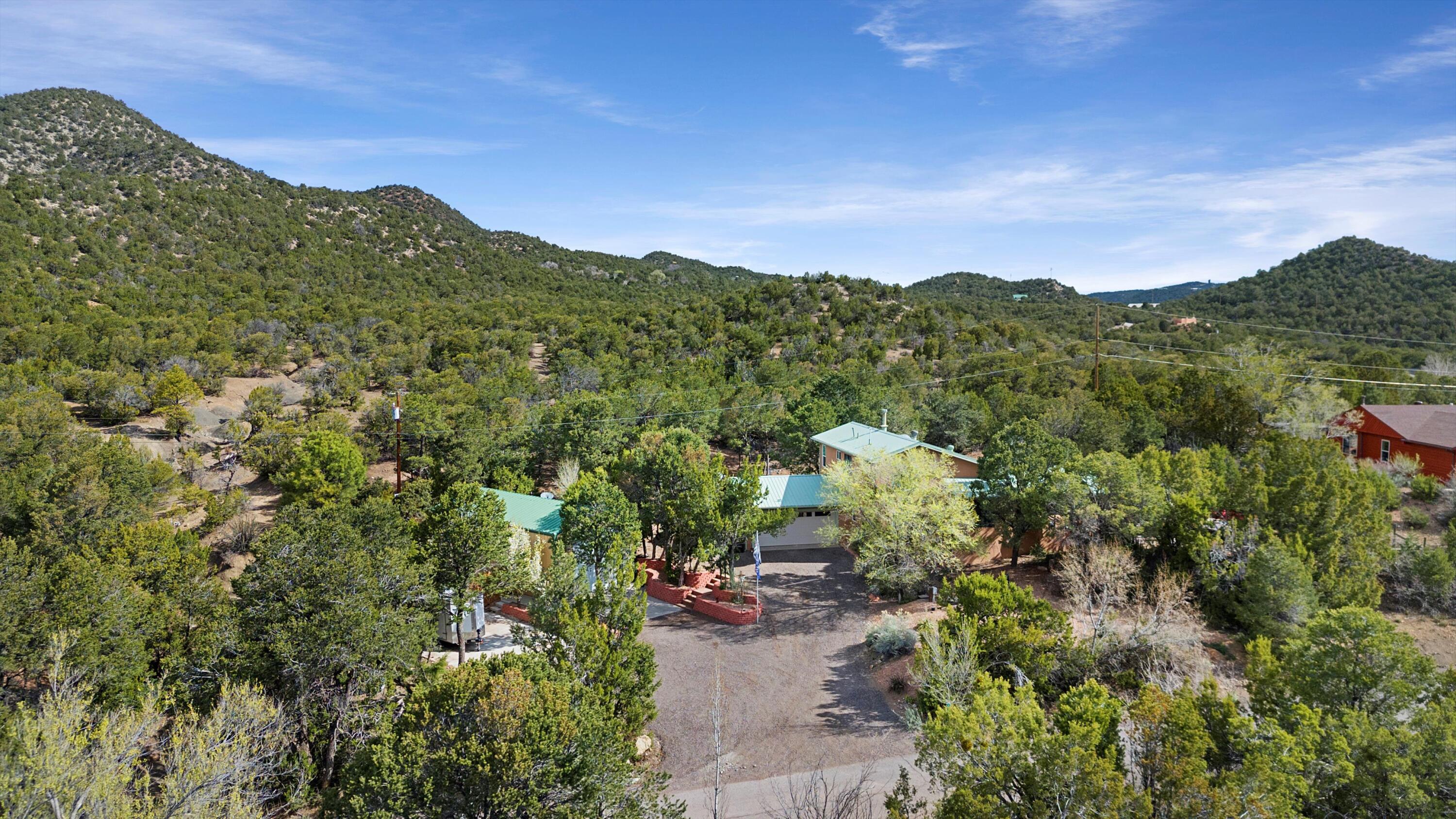 UPSCALE MOUNTAIN RETREAT in Tijeras!. With a forest as your backyard, this casa promises unparalleled views paired with loads of fine home details. Metal roof ensures durability and windows come with a lifetime transferrable warranty. Inside, enjoy your chef's kitchen with double ovens, and a built-in trash compactor! The primary suite includes a garden tub with a view and an enormous walk-in closet with built-in organization! Outdoors, the saltwater spa, expansive patio with BBQ station, and a fire pit offers endless possibilities to enjoy life! Additional amenities include a dual fuel HVAC system, a comprehensive water filtration system, and an air-conditioned RV storage/workshop with extensive capabilities for any project. So much to offer, more info in documents! Call soon!