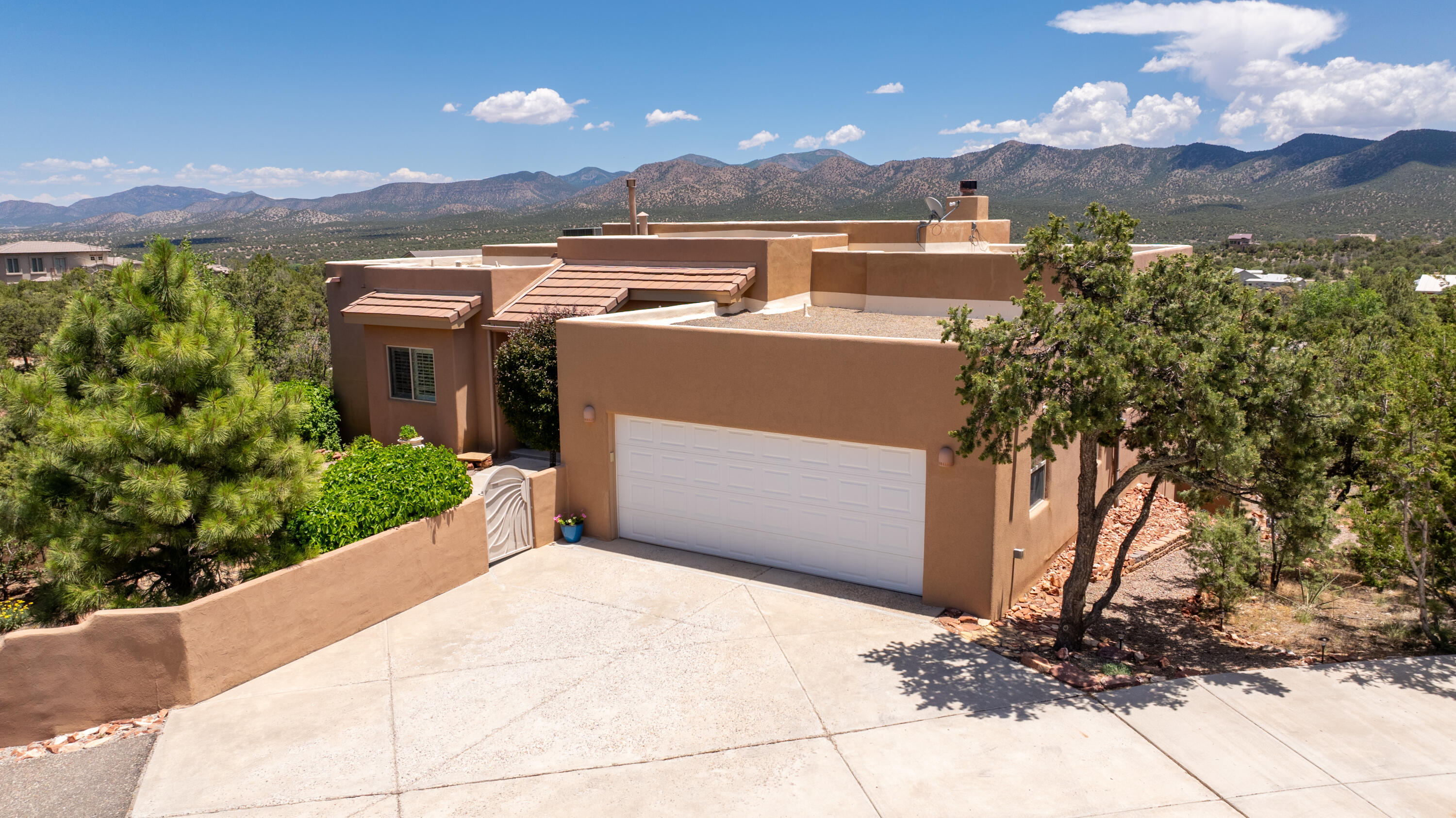 OPEN SUN 10/27 2:30-4:30 PM! Stunning modern pueblo style home with surrounding mountain views. Tucked up on an elevated, wooded corner lot in the highly sought Paako golf community, this turnkey meticulously maintained home, boasts spectacular views off the wrap-around balcony. Lots of natural light with gleaming wood floors on the upper level & luxurious finishes throughout. Abundant space to host & spread out with 4 beds, 4 baths, plus offices on the main & lower levels, storage & living spaces on both floors. Potential for multigenerational living with separate entrance on lower level. Large RV Pad with electrical hook-up. Solar powered gate for privacy. Serene outdoor spaces with balcony surround. 20 mins to ABQ. Come experience mountain luxury living.