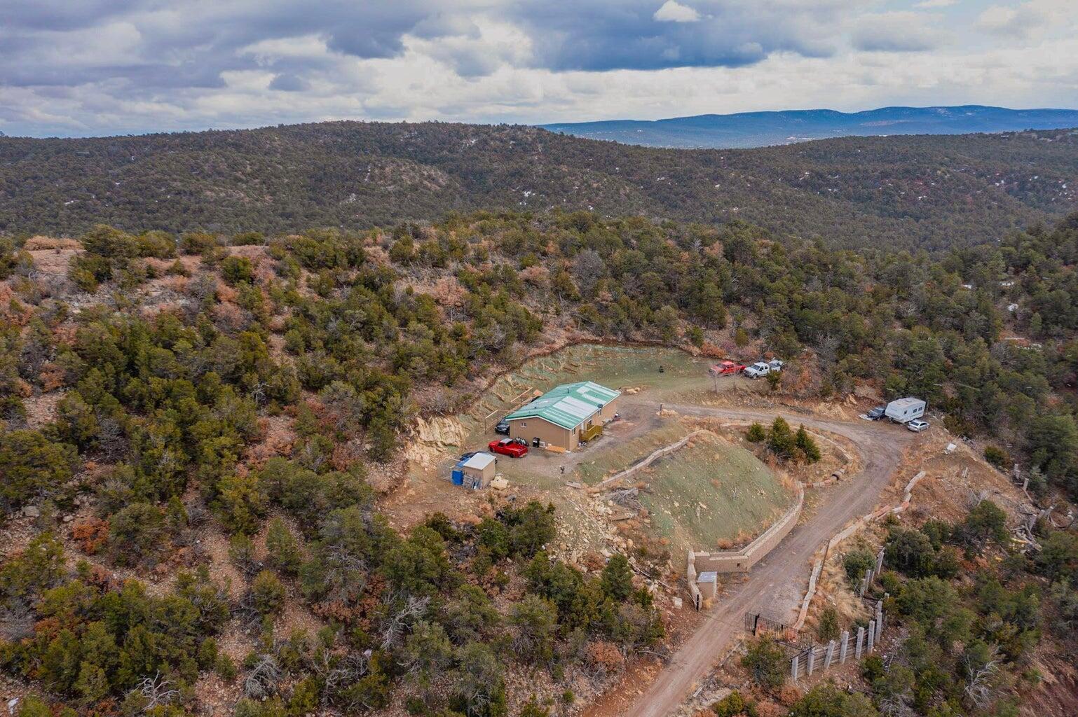 Experience serene mountain living with all the modern comforts. Nestled high on a hillside east of Highway 14, this stunning home offers breathtaking views of the Sandia Mountains. Recently renovated, the home features new cabinets, granite counters, tile floors, updated bathrooms, synthetic stucco, and solid wood doors. Boasting 4 bedrooms, 2 baths, and a large pellet stove, this residence is the epitome of comfort and style. Situated on 2 secluded acres, yet conveniently located just over a mile from amenities, this unique opportunity in the East Mountains is only a 20-minute drive from Albuquerque.