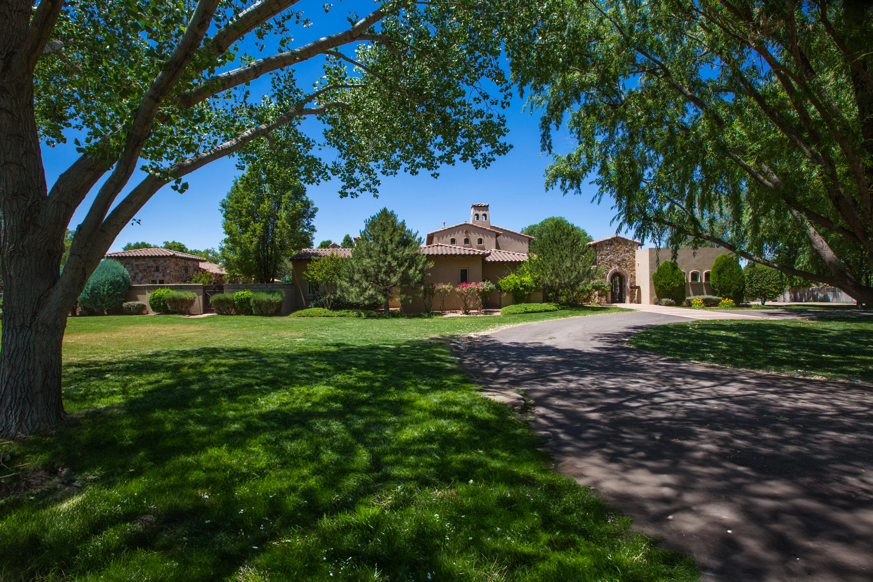 Sitting securely behind 3 sets of gates lies one of the finest homes in the Village of Los Ranchos. The design of this remarkable estate was inspired by a Mediterranean Villa and features beautiful Cantera stone columns, manicured gardens, beautiful courtyards, trickling fountains, and elegant old world charm. It is rare to find an estate of these proportions entirely on one level. This home was designed for large scale entertaining, yet is very warm and inviting for daily living. Rich furniture grade cabinetry, beautiful stone floors, elegant knotty alder doors, beautiful millwork, and classic detailing adorn this home. All bedrooms feature en-suite baths, and a fully appointed guesthouse offers flexibility. Nestled in a private and verdant setting, this home & grounds are exceptional!