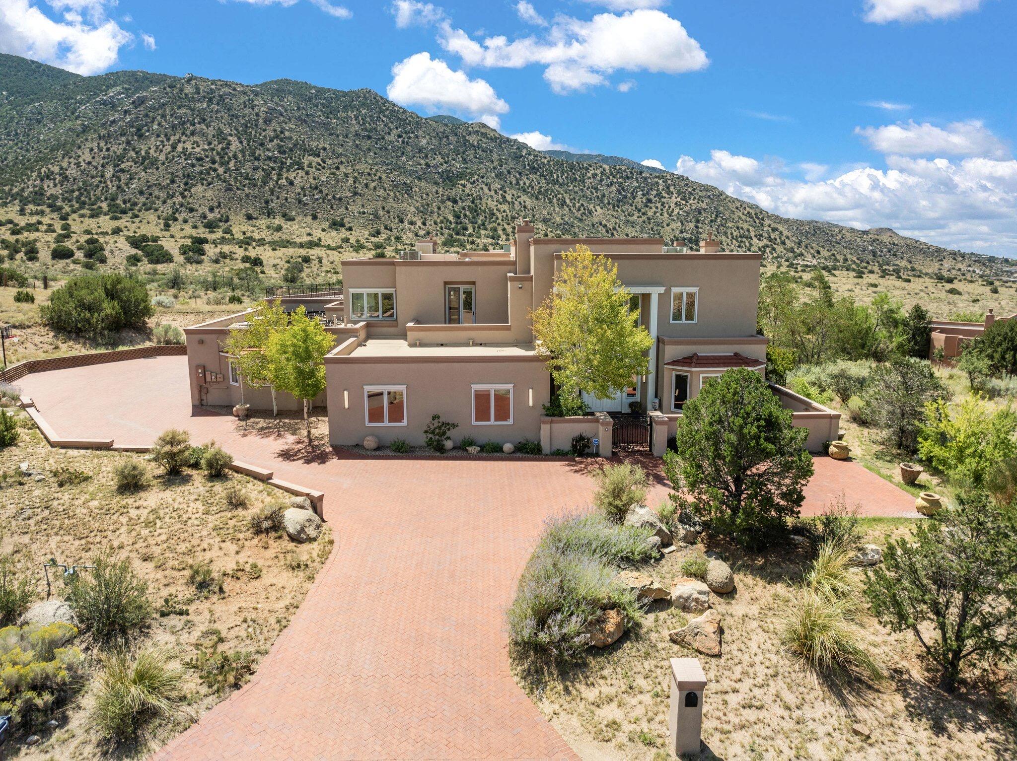 High Desert Beauty! Enter through the grand 10 ft double doors and be greeted by a dramatic foyer with a sweeping staircase and exquisite chandelier. This timeless home features elegant plaster walls and rich wood floors throughout. The magnificent formal dining room opens to a resort-like great room with a cozy fireplace and multiple sets of French doors leading to a patio with stunning mountain and city light views. Situated on a private 1.52-acre parcel backing to Open Space, this home offers ultimate privacy.The chef's dream kitchen is outfitted with top-of-the-line commercial appliances, including a 10-burner Viking stove, double wall ovens, Sub-Zero refrigerators, and a built-in freezer. Dual dishwashers and an ice maker add to the convenience,