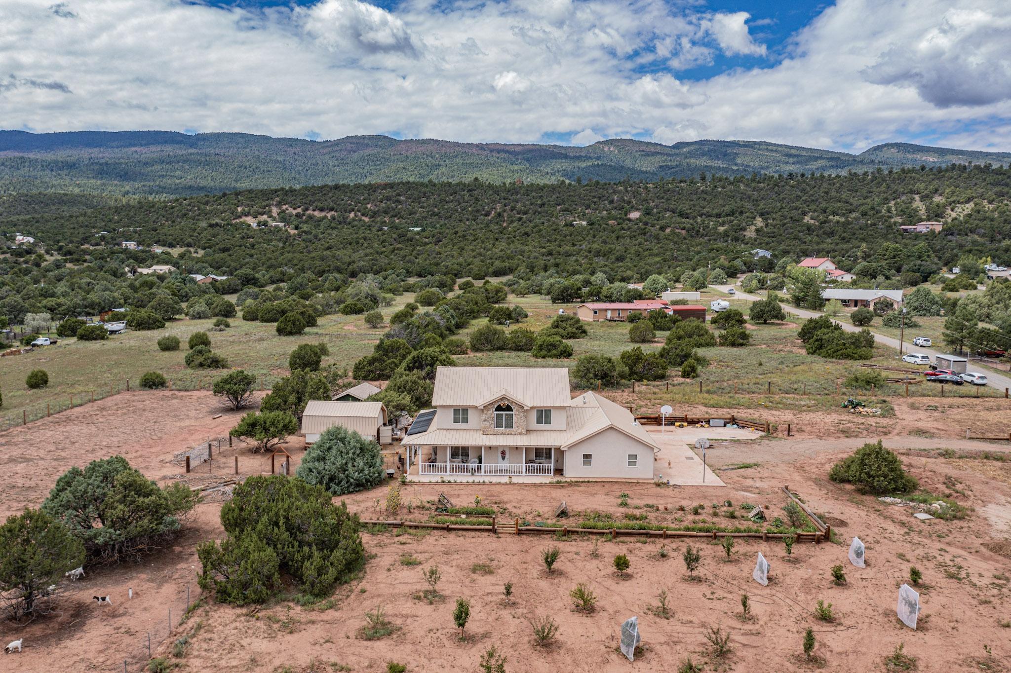 Under Contract with first right of refusal. Welcome home to your own slice of New Mexico paradise. This newer, 2022 built home has plenty of room at approximately 2850sqft, 4 bedroom, 4 bathrooms, insulated and heated oversized 3 car garage, wrap around porch, functional barn with upstairs storage/play house, all on 2.4 acres. This home is efficiently equipped with ductless mini splits and solar. Enjoy the view of the growing fruit trees from the front porch. The trees and garden are watered mainly by the 1500 gallon rain water catch storage tank. Schedule your showing today to experience this gem of a property. Parcel lot lines in photos are approximate.