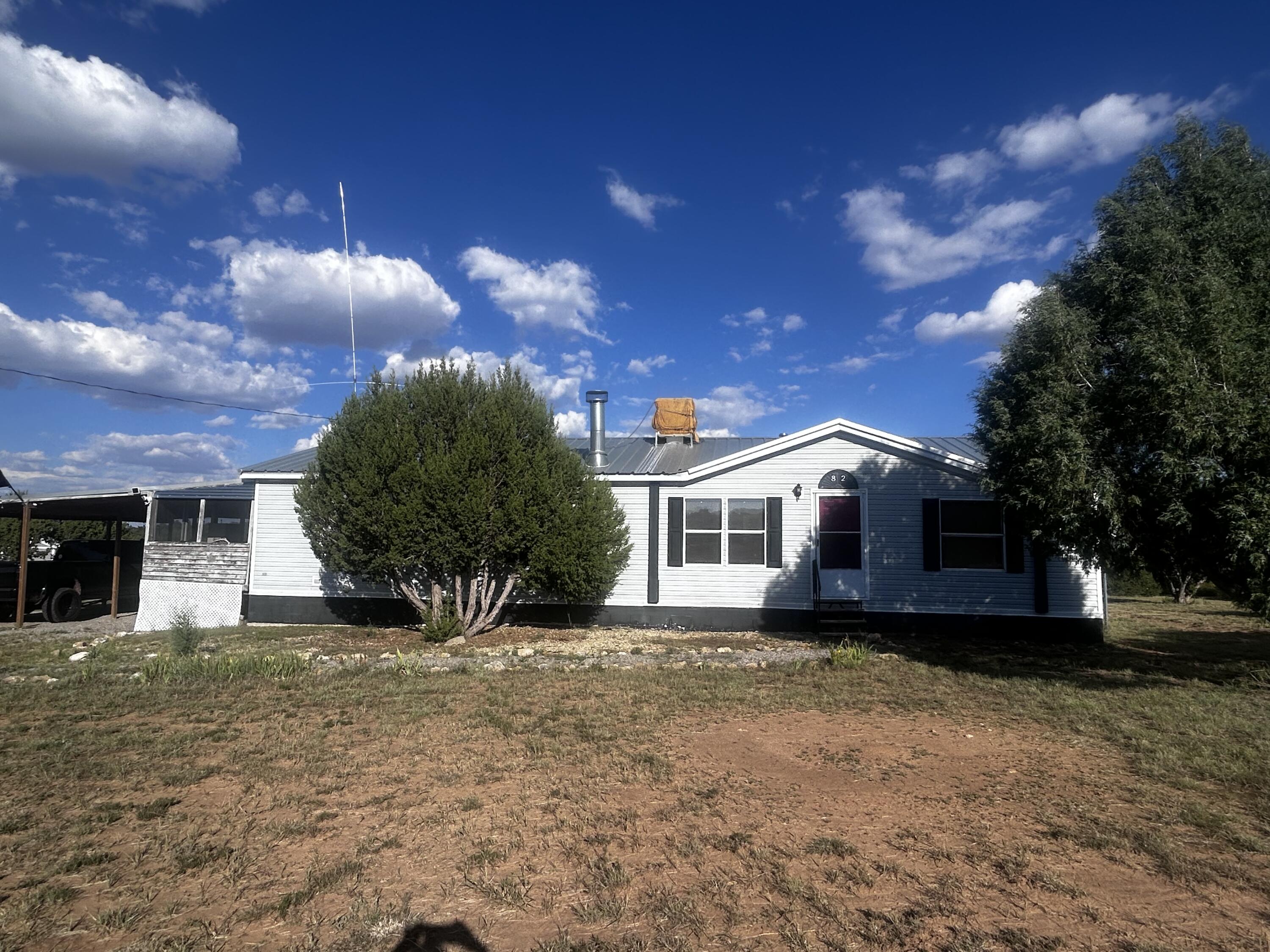 Nestled in the heart of Edgewood, NM, this peaceful retreat offers sweeping skies and stunning forest views. The meticulously maintained home features a pro-panel roof, rainwater catchment system, and generator-ready wiring. Inside, you'll find an airy layout with spacious bedrooms, tile/laminate flooring, and new stainless steel kitchen appliances. The home also includes a zero-maintenance hot water heater, wood-burning stove, fireplace, ceiling fans, two full bathrooms, and a large living room with separate dining. Outside, enjoy a lean-to for horses, two storage sheds, three quarts of red cedar firewood, and a nearly full propane tank. The community water is praised as the best around! Motivated seller- Act fast!