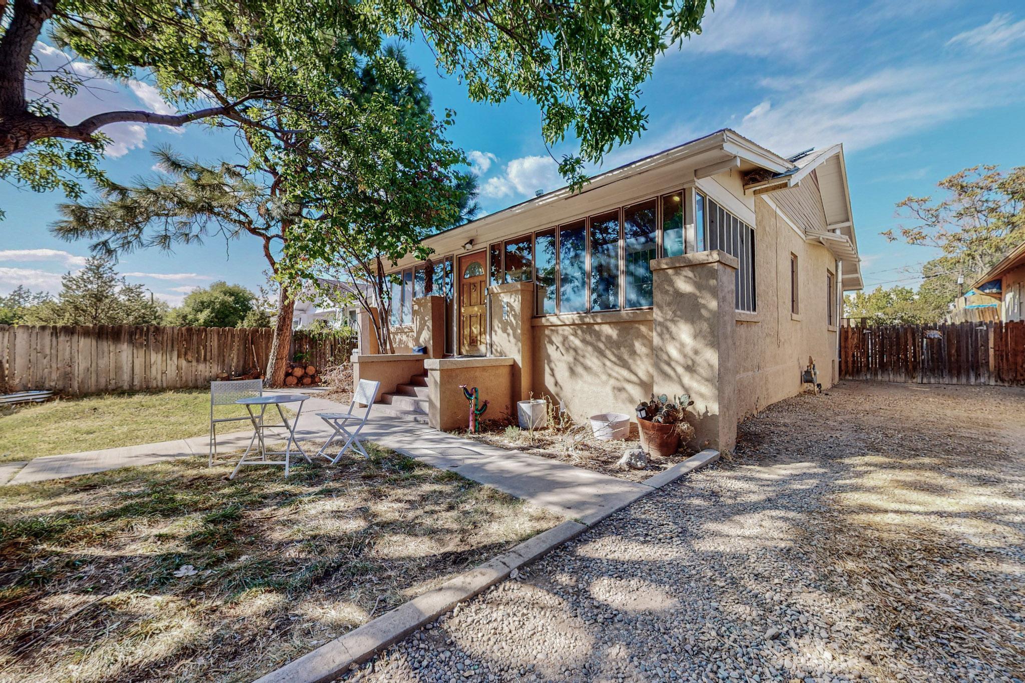 Live on one of the most historically charming tree-lined streets in Albuquerque! Snuggled between Old Town and Downtown, this Craftsman Bungalow is filled with warmth and charm. From the colorful stained glass windows to the glimmering original hardwood flooring, the vibes are immaculate. Entering through the inviting front room, you'll feel right at home. As you continue into the living room, you'll appreciate the warm glow from the original wood-frame windows, & the coziness of the wood stove. Two spacious bedrooms are on the main floor, including a perfect office nook in the primary bedroom. The dreamy clawfoot tub is a treat!A fully finished, heated and cooled basement with a half bath could be another bedroom or den.Pergola & Fruit Trees in the back yard!