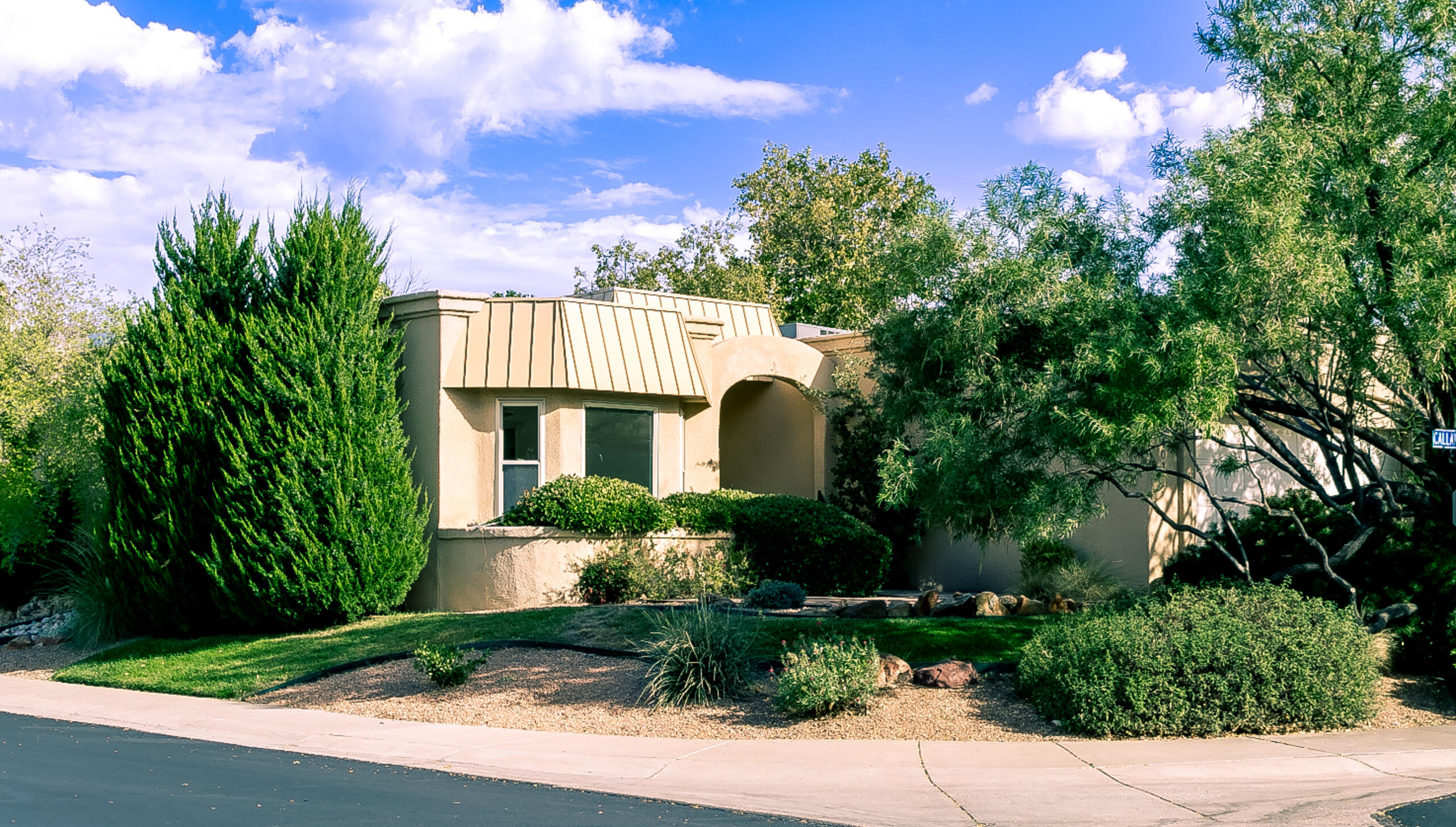 Spacious one-level home on an elevated corner lot in Village Greens at Tanoan! Expansive floorplan with large rooms, raised ceilings, 7 skylights and 2 marble fireplaces. Step-down living room with wet bar, fireplace and two sets of French doors that open to the patio. Formal dining room. Kitchen with breakfast room. Huge primary suite with fireplace, French doors, walk-in closet and bath with two vanities. Two add'l bedrooms, both with walk-in closets, + full bath with double sink vanity. Laundry room. East-facing backyard with both covered & open flagstone patios; add'l flagstone patio in front. Double garage. Refrigerated air. Thermal windows. Roof new in 2023. HOA covers common areas & community security gates.