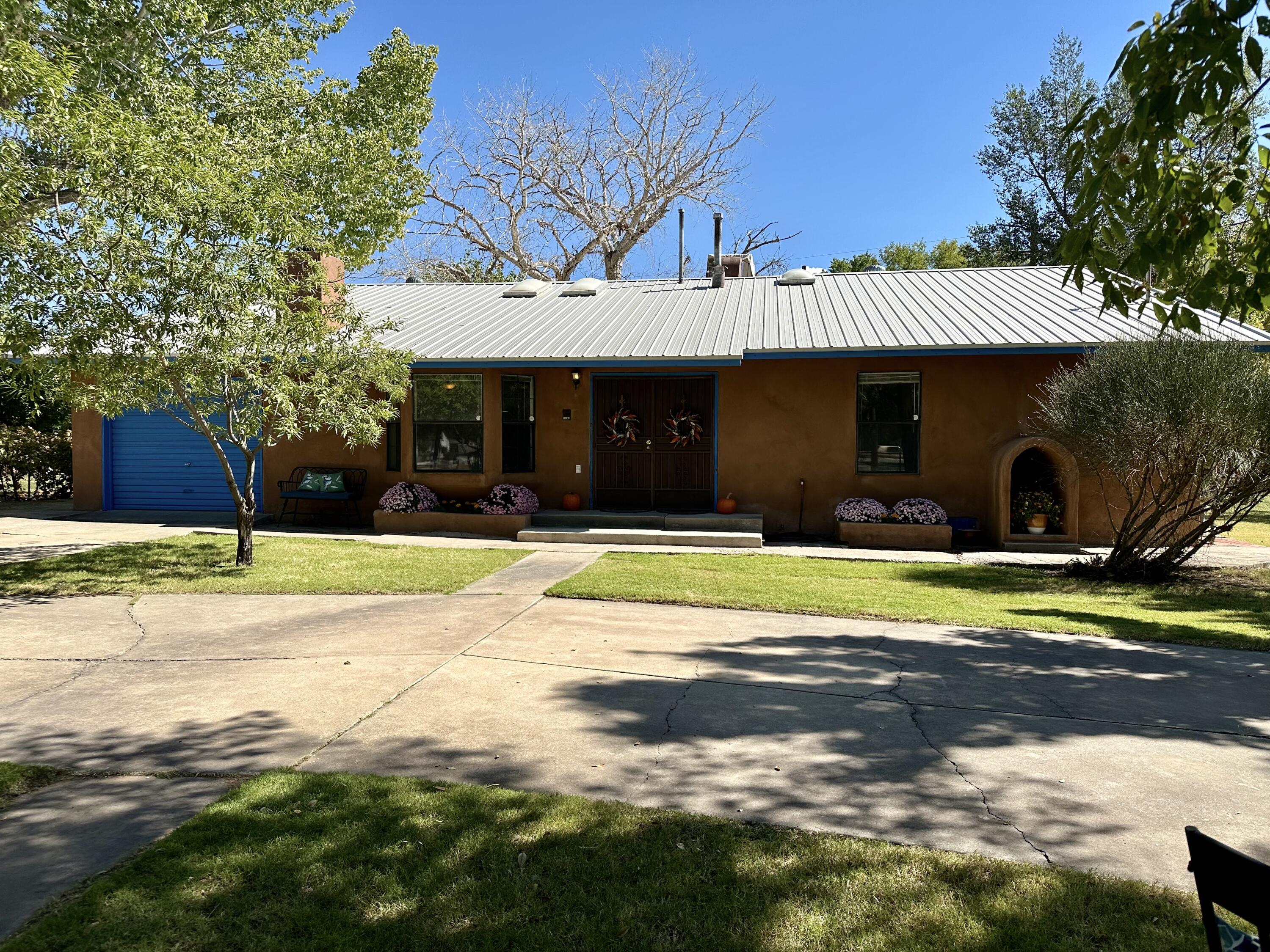 **Open House 11/9, 2:30 -4:30 pm** Welcome to this beautiful one story home located in the North Valley that sits on a .35 acre fully fenced lot with a circular drive & gated entry.  While located in a serene, country like setting, this home is just minutes away from the Bosque walking & biking trails & restaurants. The open floorplan offers 3 bedrooms, 2 baths & a kitchen with stainless steel appliances, breakfast bar, dining nook & plenty of cabinet & counter space. Enjoy the spacious living area with a custom kiva  fireplace for those cozy winter nights. A heated sunroom perfect for an office/rec room & has a separate storage. Has a metal roof, and many updates. Landscaped with many varieties of fruit trees, ground cover & an irrigation well.  Backyard access & plenty of room for an RV