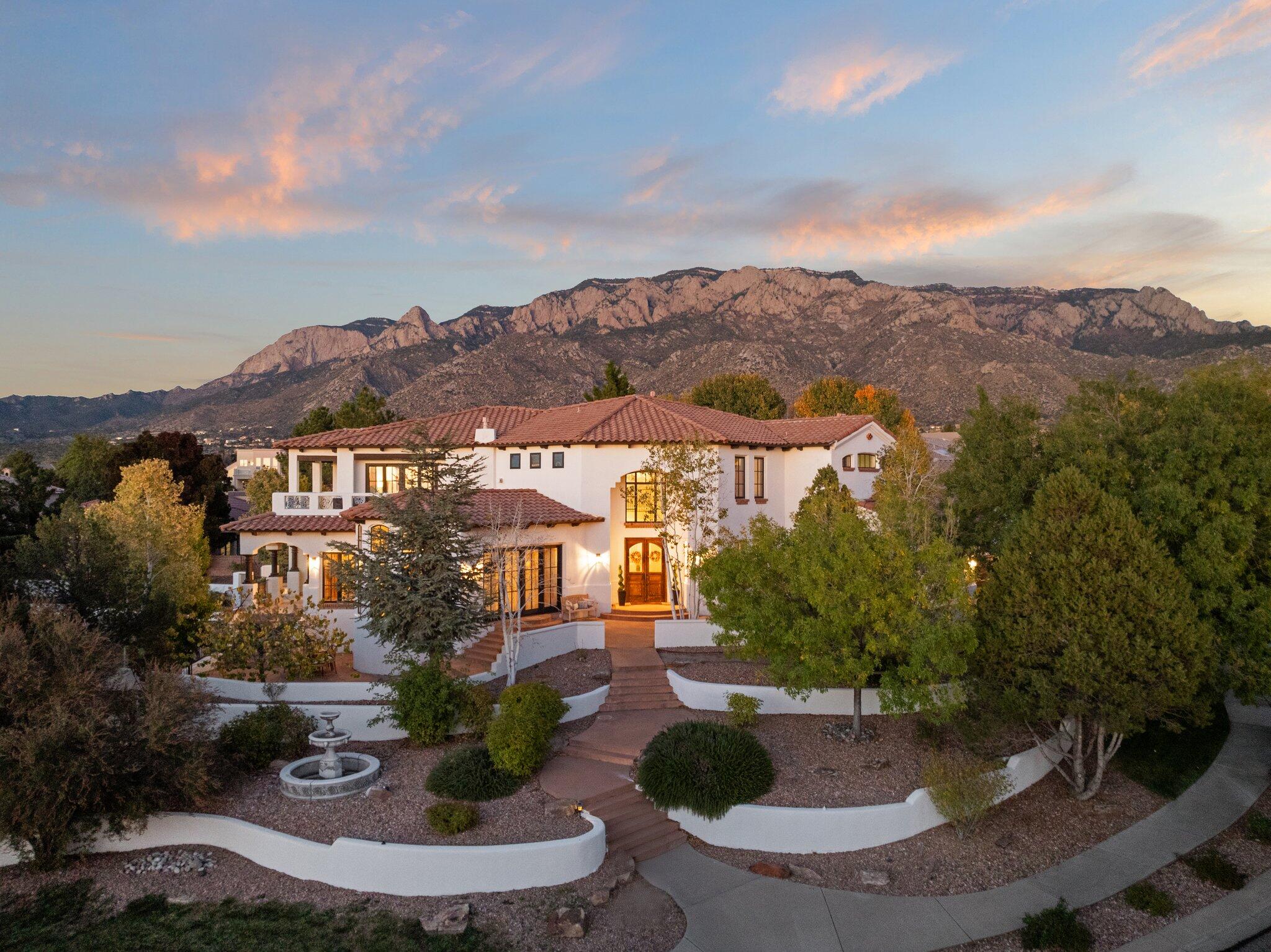 Welcome to an extraordinary custom home in Primrose Point! This Mediterranean-inspired residence boasts impeccable attention to detail and expansive indoor and outdoor spaces perfect for entertaining. The main level features a large open kitchen that flows into the family room, with patios offering stunning views of the city and Sandia Mountains. A sweeping staircase, cathedral ceilings, and wood beams elevate the ambiance. Step into the outdoor oasis with a pool-ready backyard and a spacious 700-square-foot Casita, ideal for guests. The beautifully landscaped yard bursts with vibrant blooms from spring through fall. Inside, a versatile downstairs area offers space for gatherings, a gym, yoga room and a theater.  Don't miss the chance to make this marvelous estate your own!