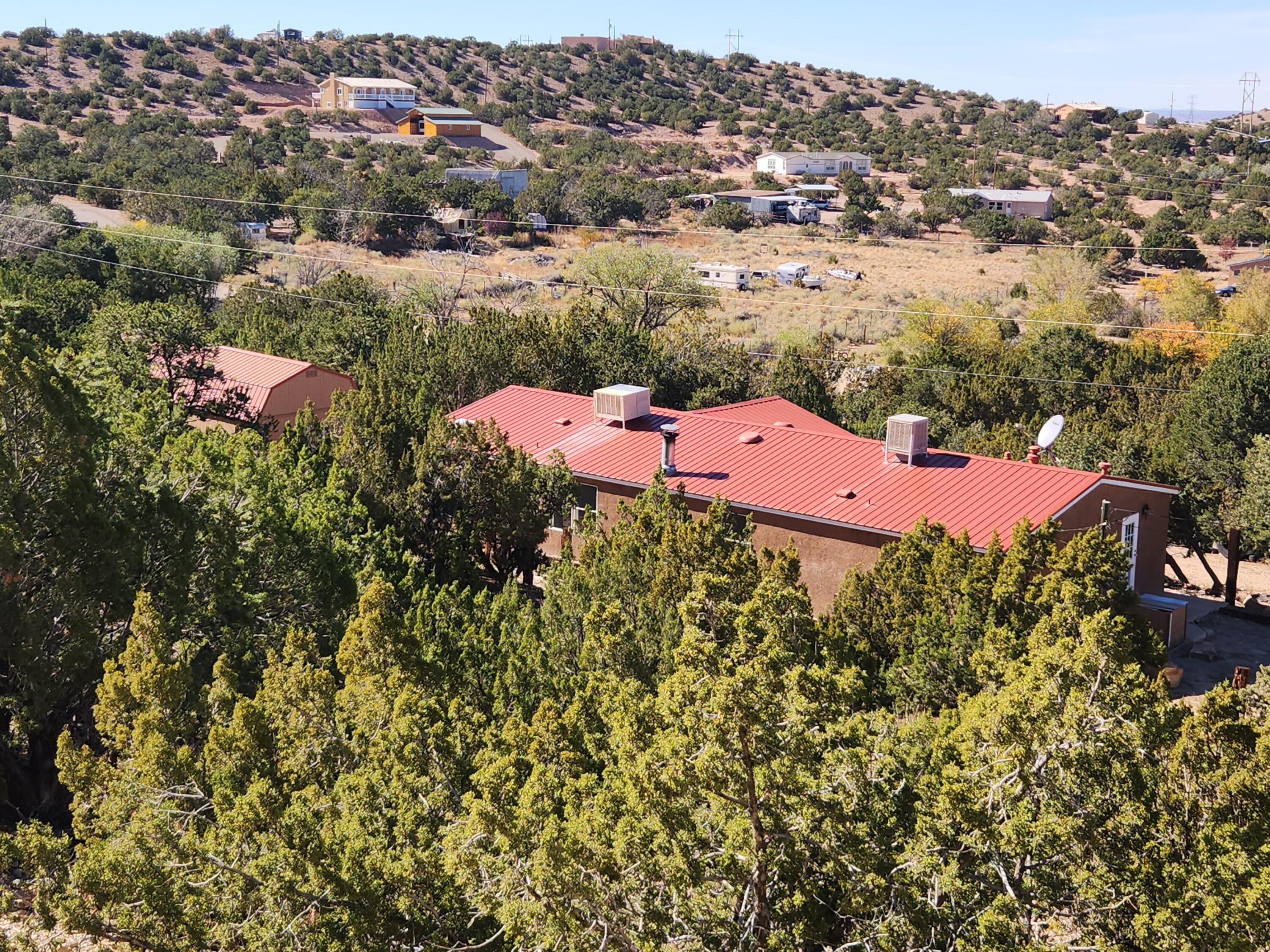 OWNER FINANCING! $285,000. 3 BEDROOM, 2 BATH HOME ON 3 ACRES! Affordable 1654 sq ft manufactured home on permanent foundation in Placitas, with 1 car garage/barn. This is a serene 3 acres with lots of Pinon & Juniper, giving you tons of privacy. There is room for horses and other animals; no covenants, so horses, chickens & goats, etc, are allowed! New flooring (laminate & carpet) in bedrooms, living room & kitchen! Beautiful, nearly new, low maintenance pro-panel roof! Split floor plan, so the primary suite is separate from the 2 guest bedrooms. Primary bath has oversize jetted tub and separate shower. There is plenty of room for a studio, guest house, shop, etc! Owner financing available with 20% down, at 7% interest, 20 year amortization with a 2 or 3 year balloon.