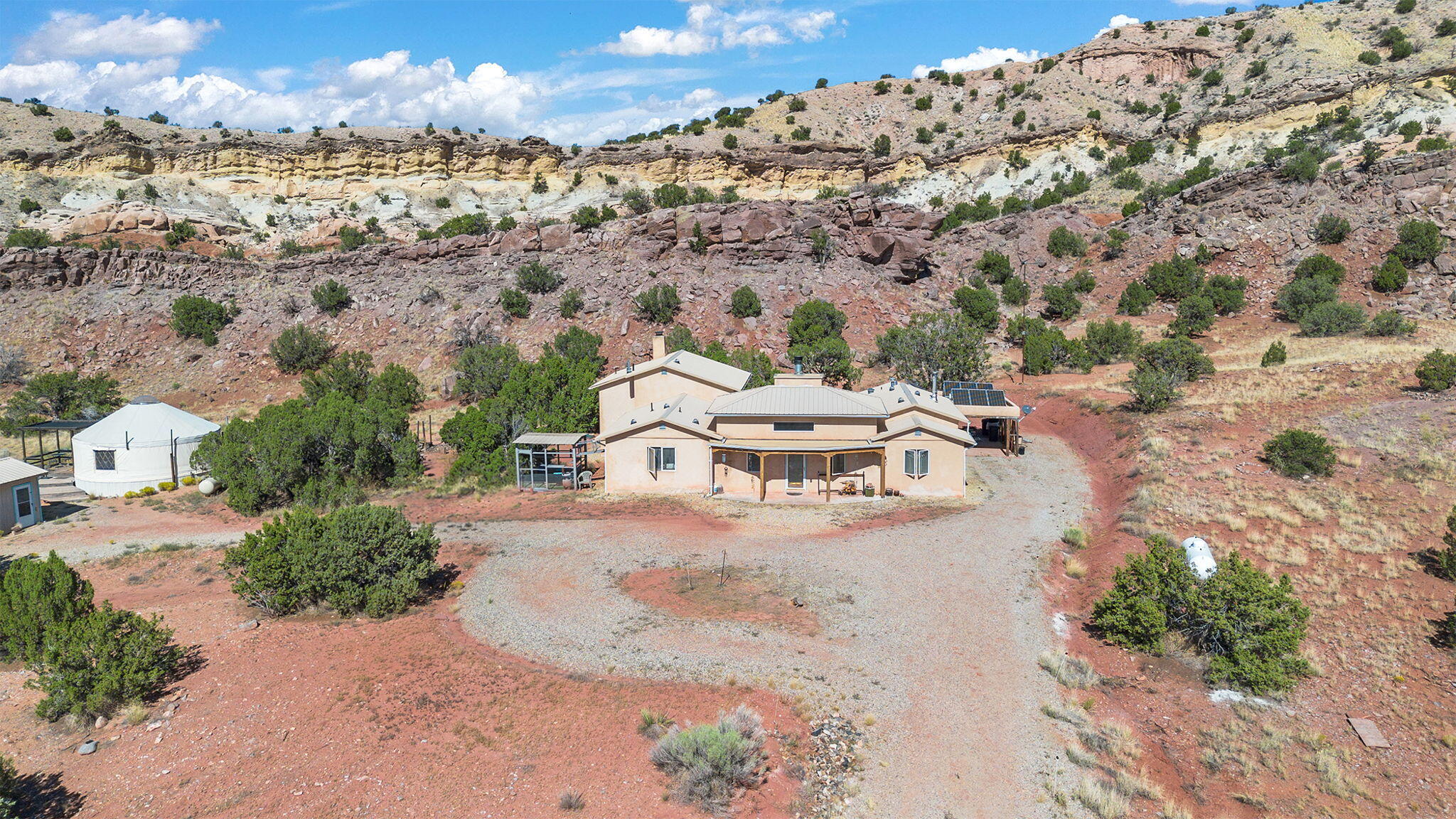 Almost 10 Acres of property nestled in the tranquility of the Sandia foothills, this off-grid property contains a unique opportunity to experiencemodern luxury alongside sustainable living practices. Sunsets & star gazing are unparalleled beneath the unobstructed sky. Home has been consistentlyupgraded & now includes a brand-new guest bathroom, new paint in every room. Full custom wood built-ins within the master bedroom. Host your own pizza parties with the built-in wood fire pizza oven! A secluded courtyard looks out to the beautiful rock formations of backyard & an overlook plateau that was originally dubbed ''meditation ridge.'' Large heated/cooled yurt (not included in sq/ft) has own full kitchen, bathroom, and a spectacular view of the mountains!