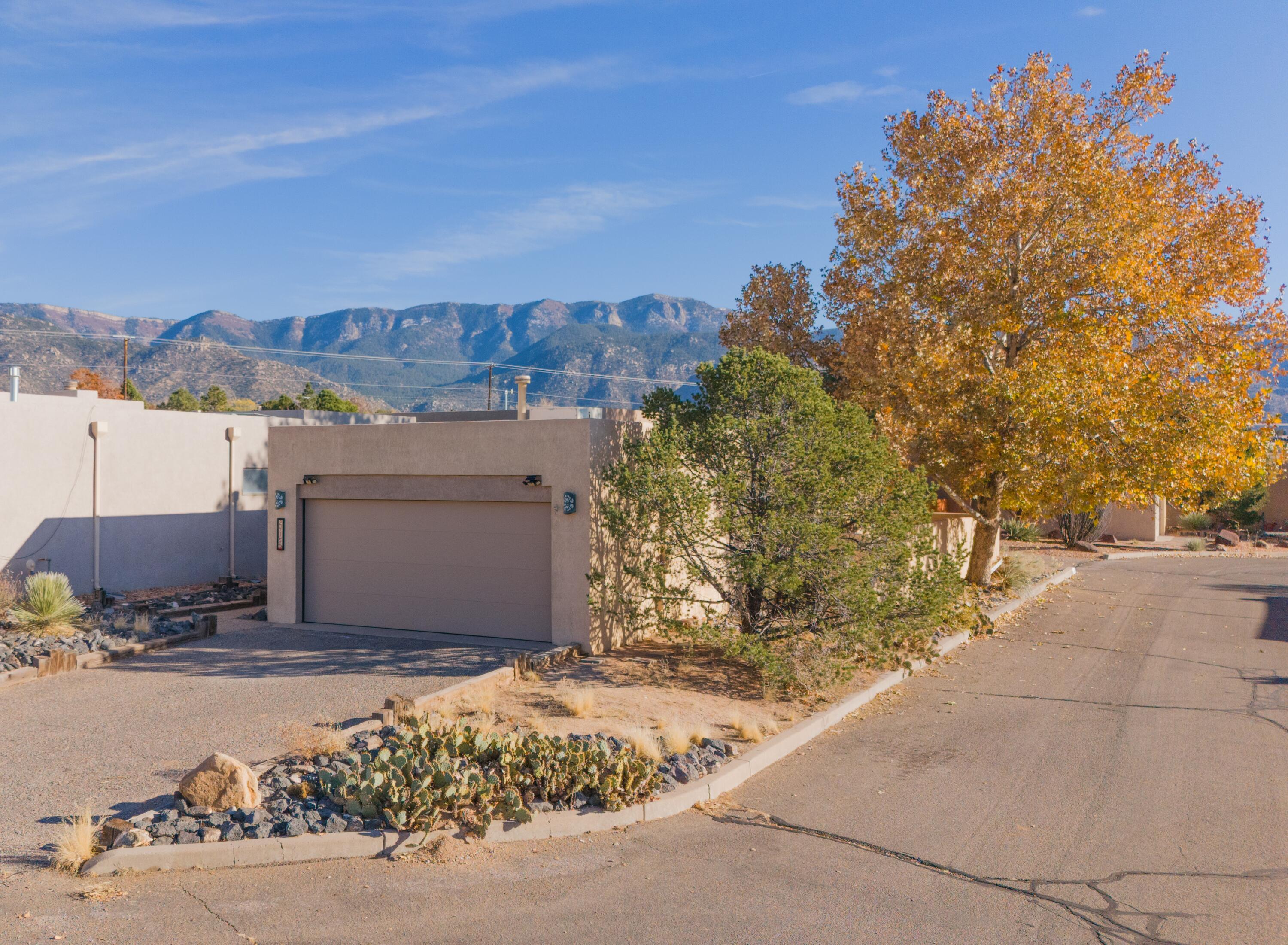 Sitting near the base of the Sandia's, this move-in-ready home offers 1,618 sqft of living space, with 3 bedrooms, 2 bathrooms. The low-maintenance beautiful Southwestern landscape complements the surrounding natural beauty. The spacious living room boasts tall ceilings and large windows, framing breathtaking views of the Sandia's in the backyard. The recently updated kitchen includes brand-new appliances and sleek stone countertops. Freshly painted interiors, new carpeting, and updated tile in the primary bathroom enhance the home's modern appeal. The primary bedroom offers access to a private patio. Original solid wood doors reduce noise and create a peaceful atmosphere. Exterior offers new garage door and copper fixtures.