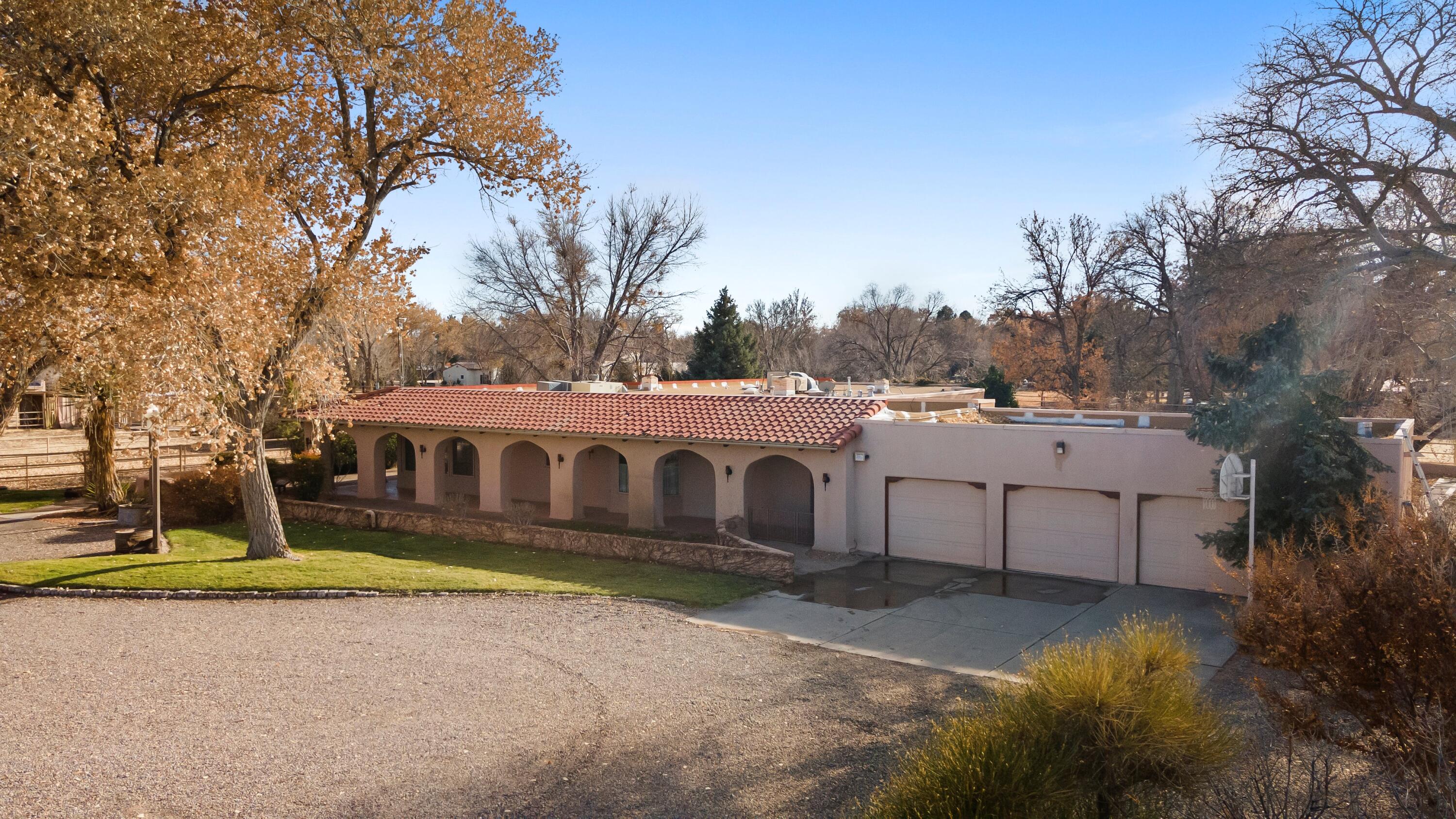 Welcome to this extraordinary 4,500-square-foot SW Pueblo-style estate, located in the prestigious Los Ranchos area in Albuquerque's picturesque North Valley. This single-level home is a rare find, set on 3.6 beautifully landscaped acres with two additional parcels, offering endless possibilities. The second parcel spans 1.9 acres and includes multiple outbuildings: a 40' x 50' horse barn, carports, and livestock stalls. The third parcel, 1.82 acres of well-maintained field space, provides versatility for equestrian, agricultural, or recreational uses. The home's exterior exudes timeless charm, with sprawling verandah, open fields, a pool and hot tub. Inside, you'll find authentic brick flooring, rough cut beams, and T&G ceilings that showcase the craftsmanship of a bygone era.