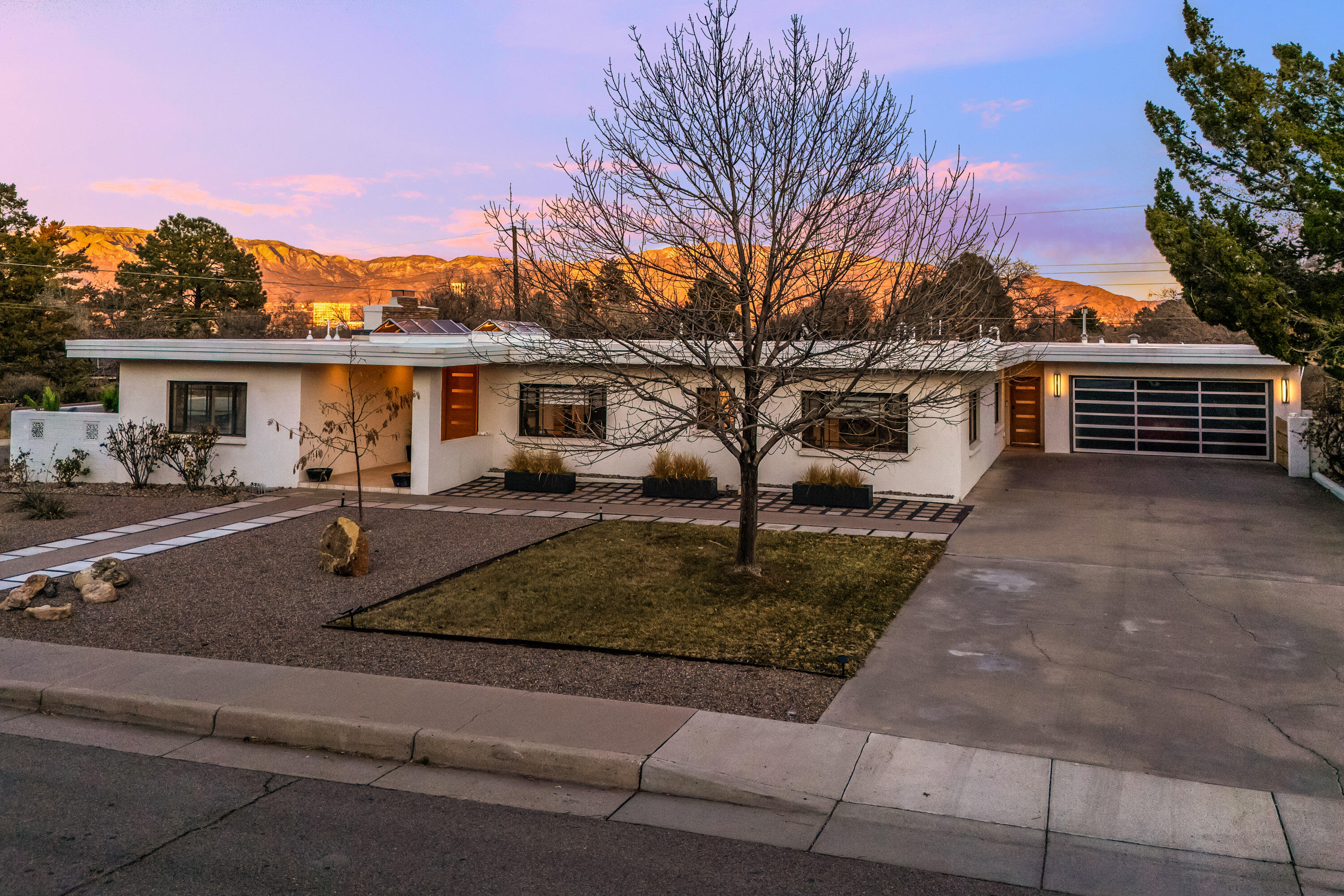 Unparalleled luxury in this meticulously rebuilt mid-century modern home, where elegance meets functionality. This spacious 1 story residence has abundant natural light, accentuated by skylights and gallery lighting in the great room, ideal for dining, music, and entertaining. With a hot tub on the primary suite terrace and 5 versatile Bdrms (2 used as offices), this home easily accommodates multi gen living w/an ADA-compliant bathroom. With Sandia views, in a quiet neighborhood near Ridgecrest and Nob Hill's Co-op and restaurants, this gem includes smartphone-controlled thermostats, keyless door locks, irrigation controls, cameras, and ADT security system. 2  fireplaces--1 Prairie stone w/ gas jets.  Xeriscaping plus a lush grass area in the backyard  with garden beds, fruit trees,