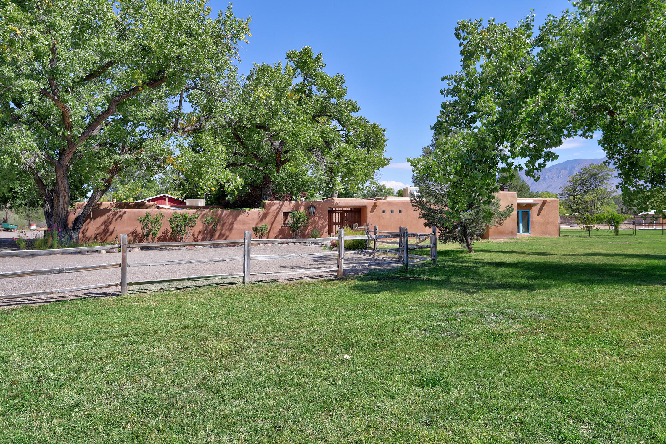 Charming adobe hacienda full of character set on nearly 2 acres in the Corrales greenbelt steps from the bosque, w/ its miles of walking/riding trails. The 4-bedroom home + office showcases timeless details like brick & Saltillo tile floors, beamed ceilings & a spacious living room w/ signature fireplace. Kitchen boasts abundant storage, Viking stove & cozy banco. An in-law suite w/ its own entrance features an efficiency kitchen, perfect for guests or multi-generational living. Recent updates include newer roof (2020) & evaporative cooler. 2 wells. Equestrians & hobbyists will love the 1,500+ SF 4-stall barn, complete w/ tack room & workshop. Relax by the tranquil pool or listen to morning birdsong w/ stunning mountain views. Bring your animals & green thumb to this Corrales country gem!