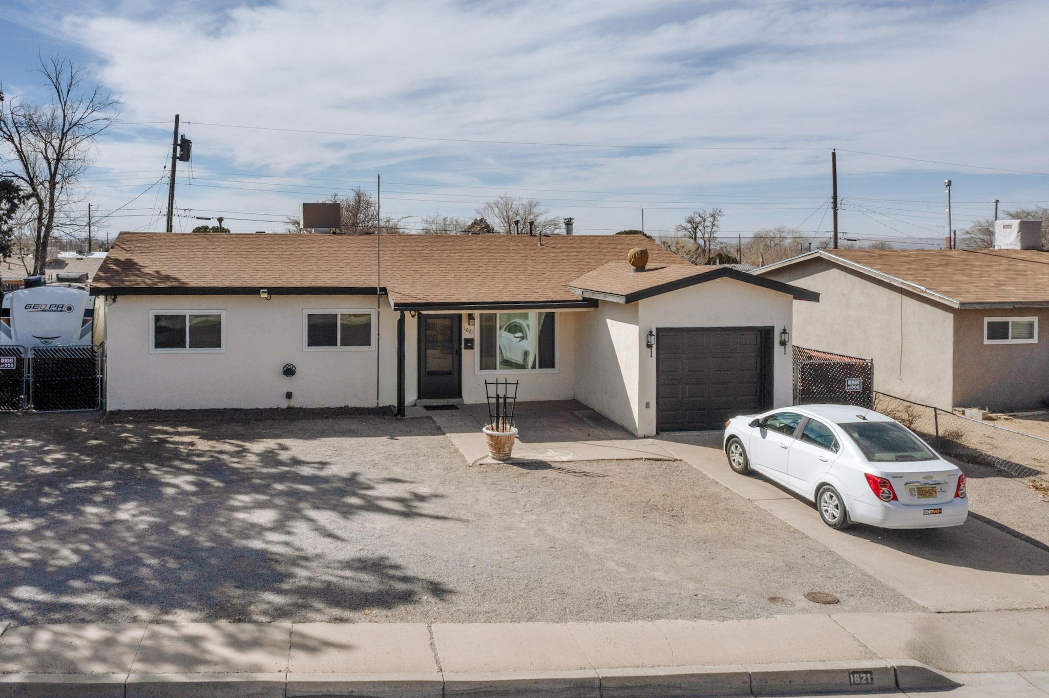 This comfortable 3-bedroom, 2-bathroom home in Albuquerque's Northeast Heights offers a blend of practicality and convenience. The spacious kitchen features ample storage and a pass-through to the living room, creating an open feel. Ceiling fans, skylights, and abundant lighting enhance the ambiance throughout the home. Durable wood laminate and tile flooring provide both style and resilience. The home is equipped with an efficient rooftop MasterCool system, wall heaters, and a wood stove. Electrical updates include a new 200-amp service, enhancing the home's safety and capacity. Outdoor features are plentiful, including a covered patio, a second driveway, a detached workshop, and a large storage shed. The location offers close proximity to schools and shopping center