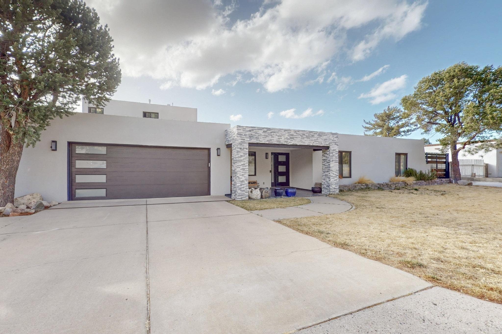 Stunning 5 bedroom, 4 bath home with mountain sounds and views features two Master Suites. Located at the base of the Sandia Mountains, this stunning home boasts raised ceilings throughout its living spaces. A four panel glass slider seamlessly connects the kitchen and dining room to breathtaking views of the city below. Step outside to enjoy an inground gunite pool, perfect for hosting all your summer gatherings. A large water feature in the backyard enhances the peaceful ambience of the outdoor space, and the upper level of the tiered yard is ready for your finishing touches. Inside, you'll find new flooring throughout, a dream kitchen, and updated bathrooms. Gated oversized driveway on N side. SELLER TO FINISH UPPER TIER OF BACK YARD WITH SOD/GRASS.