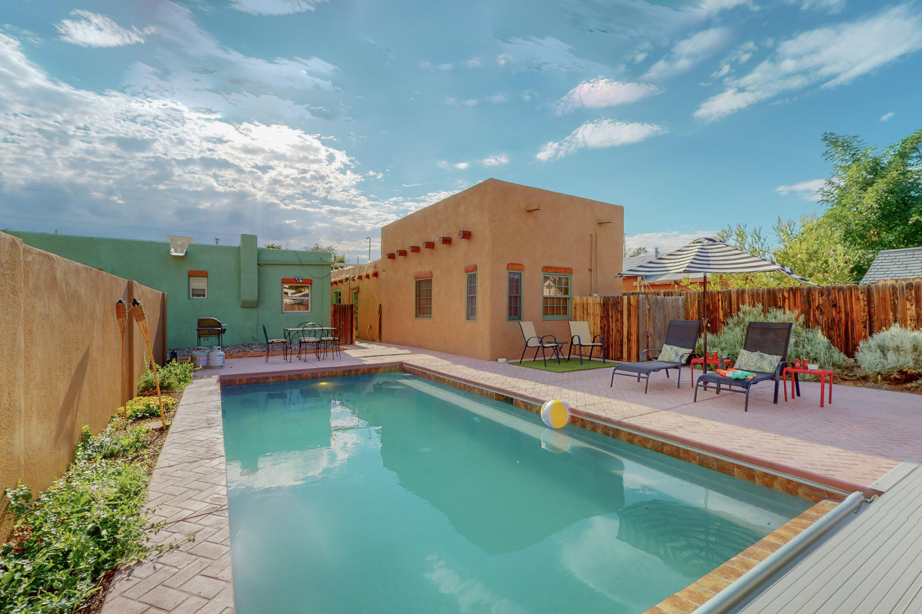 Two adobe homes + saltwater pool on a private oversized lot in the coveted Sawmill District -- just blocks from Sawmill Market, museums, and Old Town. The front home is a beautifully updated, fully furnished short-term rental with granite countertops and classic Saltillo tile. The back home is rich in New Mexican soul: two kiva fireplaces, custom brick floors, vigas, and nichos. The 2022 kitchen remodel features handcrafted cabinetry, solid-surface counters, stainless appliances, and a wine fridge. TPO roofs (2021/22), updated systems, and proven rental history make this a turnkey opportunity for investors, creatives, or anyone craving flexible living with serious charm.Live in one. Rent the other or keep both for the ultimate sawmill retreat. Seller will consider all offers!