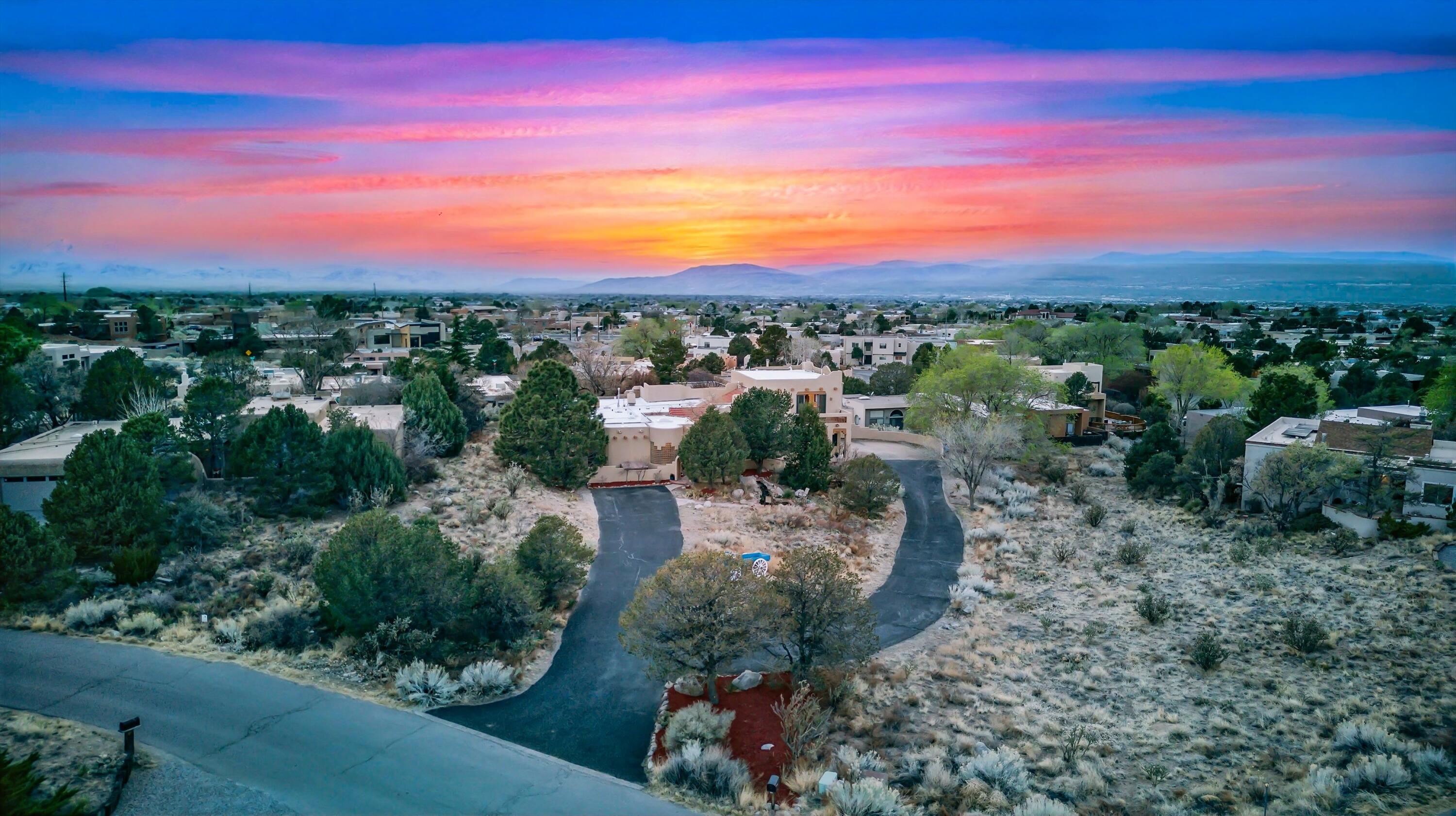 Nestled in the sought-after Sandia Heights, this stunning 5-bed, 4-bath home spans 4,426 sqft of luxurious living space. The inviting front music sunroom, intimate kitchen, and cozy family room make this home the heart of comfort. A second living room is perfect for hosting or enjoying time with loved ones. Two expansive decks offer stunning views of the Sandia Mountains, sunsets, and starlit skies. The spa-like primary suite is a private retreat. Set on spacious grounds with many rose bushes, fruit trees, and a peaceful water feature, this home offers both beauty and tranquility. There is even a secret room that's perfect for a wine cellar, storage, or hiding things you don't want anyone to fine! Located in a top-rated school district and priced way below appraised value! Welcome Home!