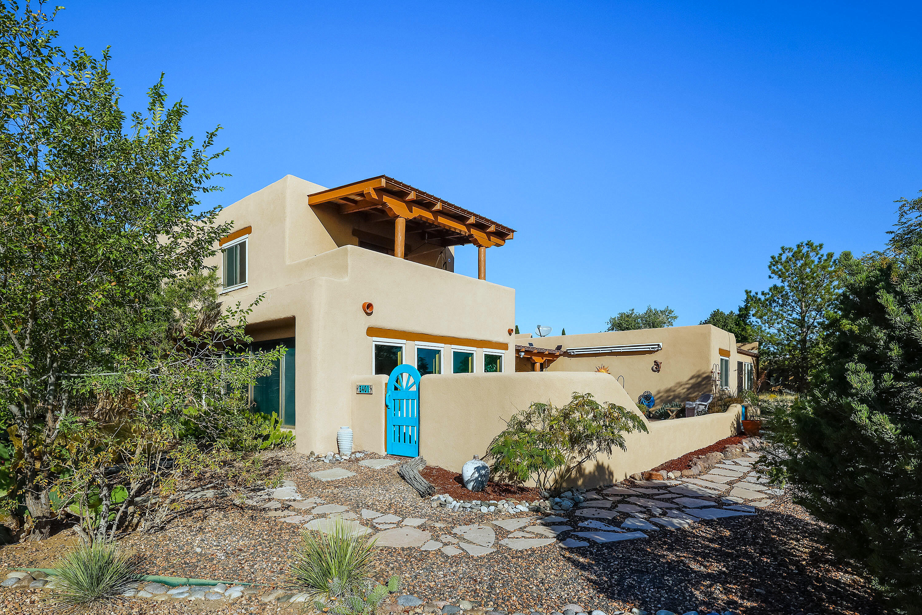 Perched above the Rio Grande with breathtaking views of the Bosque, downtown Albuquerque, and the Sandias, this custom Southwestern home is a rare find. Rich in character, it features exposed adobe walls, raised beamed ceilings, and two serene courtyards. The spacious gourmet kitchen offers granite counters, a cooktop island, and abundant custom cabinetry. Two primary suites--one up, one down--provide flexibility, each with private baths and outdoor access. The upper suite boasts hardwood floors and a view deck perfect for sunrise or sunset. Passive solar design enhances comfort and efficiency.
