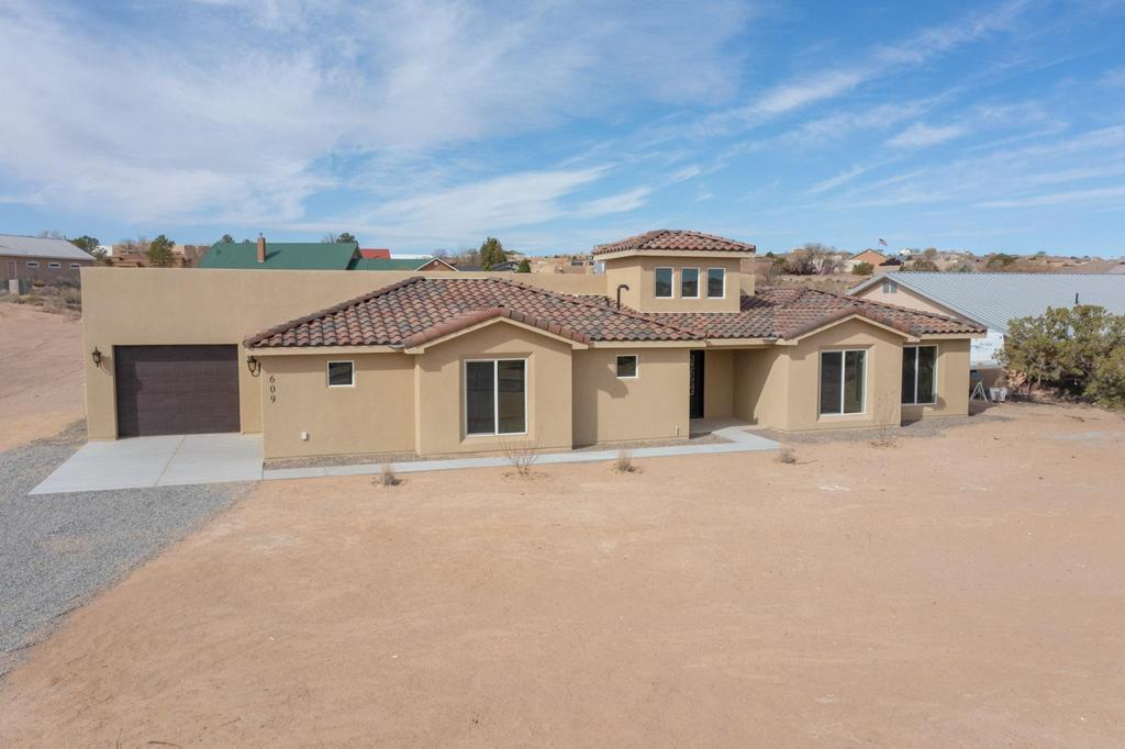 Exceptional newly built home on 1/2 acre with desirable side yard access on a paved road.  The beautifully appointed home includes glass, wood and iron front door in the majestic entryway with tall ceiling and windows, upgraded alder cabinets with under cab lighting, quartz countertops and tile flooring throughout, solid wood doors throughout, patio doors with built in blinds, large windows and skylights, serene stand-alone tub with waterfall faucet, walk in shower with gorgeous tile work, huge closet with built in cabinet, eco-friendly tankless water heater, extended 2 car finished garage with extra storage space, windows and enclosed water heater room. All this in a convenient area of Rio Rancho surrounded by custom built homes accessible from Unser or Broadmoor