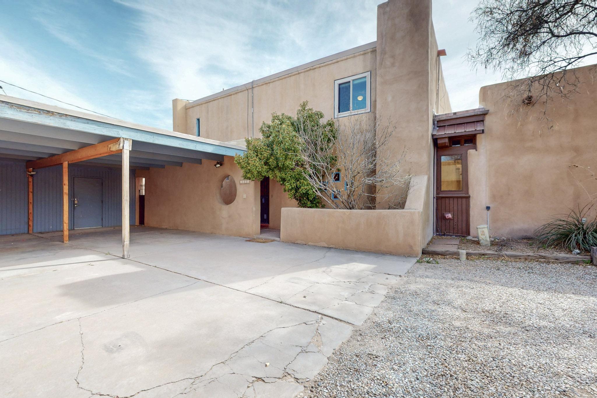 Live nestled among history in an adobe community along Guadalupe Trail! Perfectly situated at the end of a row of dreamy homes is this two-story architectural gem in Guadalupe Del Prado.Filled with intention, features include warm brick flooring paired with adobe texture and stained glass windows, & a kiva fireplace. The modernized kitchen has plenty of counter space and room to move about comfortably. An enclosed back patio with a hot tub is perfect for relaxing with your morning coffee and unwinding at the end of a dayThe primary bedroom suite has a bonus office room, walk-in closet, and en-suite bathroom. The additional two bedrooms and bathroom are spacious. A carport comfortably fits two cars. A short walk to the beautiful Los Poblanos Open Space and a community pool.