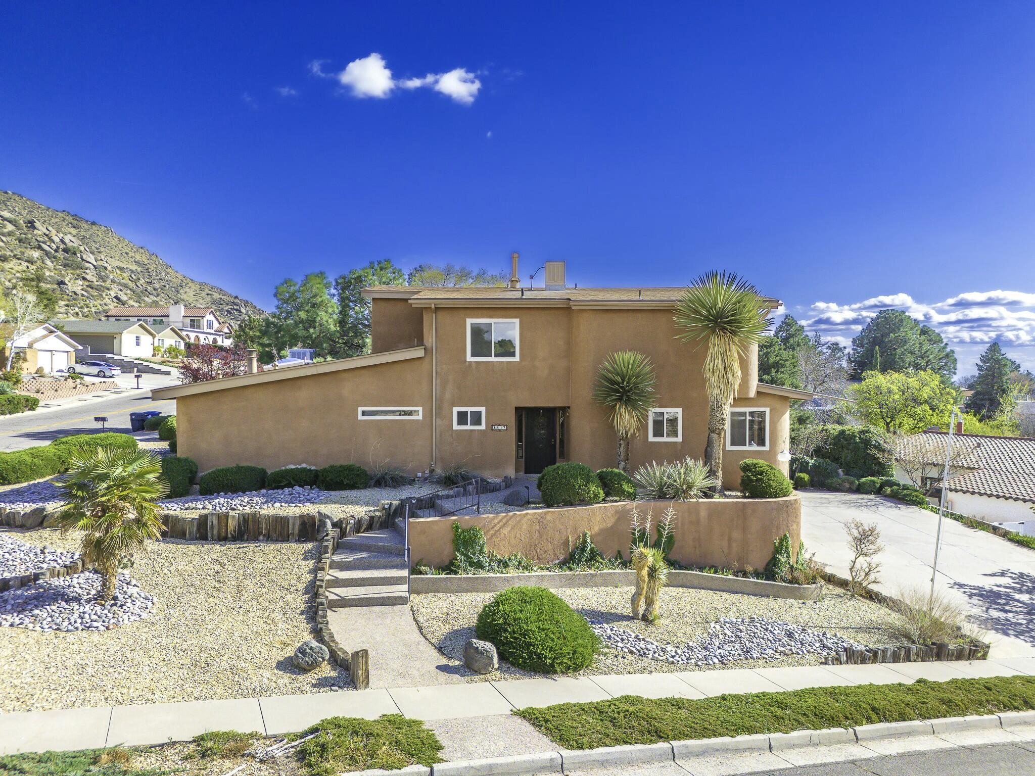Perched in popular Glenwood Hills South, this custom two-story gem captures stunning mountain views by day and twinkling city lights by night. The spacious great room features soaring ceilings, passive heat trombe panels providing amble warmth, and a retro standalone wood-burning fireplace. Perfect for entertaining, it includes a stylish wet bar and an open, light-filled layout. The updated kitchen dazzles with granite counters, an island cooktop, and timeless wood shutters. The main-level owner's suite is a warm, inviting retreat with a cozy kiva fireplace, dual sinks, and two walk-in closets. Upstairs offers three additional bedrooms. Below, the 3-car garage includes a workshop, storage, and half bath--with a lift for easy access to the main floor. Full of charm, character, and comfort!