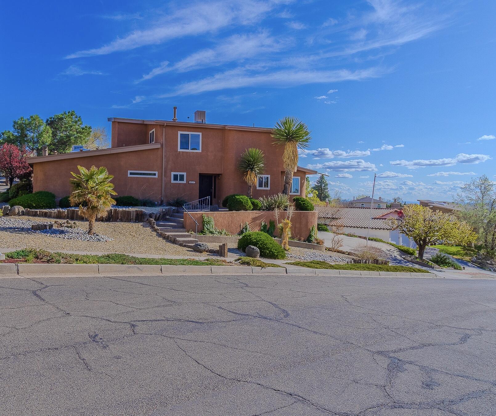 Perched in popular Glenwood Hills South, this custom two-story gem captures stunning mountain views by day and twinkling city lights by night. The spacious great room features soaring ceilings, passive heat trombe panels providing amble warmth, and a retro standalone wood-burning fireplace. Perfect for entertaining, it includes a stylish wet bar and an open, light-filled layout. The updated kitchen dazzles with granite counters, an island cooktop, and timeless wood shutters. The main-level owner's suite is a warm, inviting retreat with a cozy kiva fireplace, dual sinks, and two walk-in closets. Upstairs offers three additional bedrooms. Below, the 3-car garage includes a workshop, storage, and half bath--with a lift for easy access to the main floor. Full of charm, character, and comfort!
