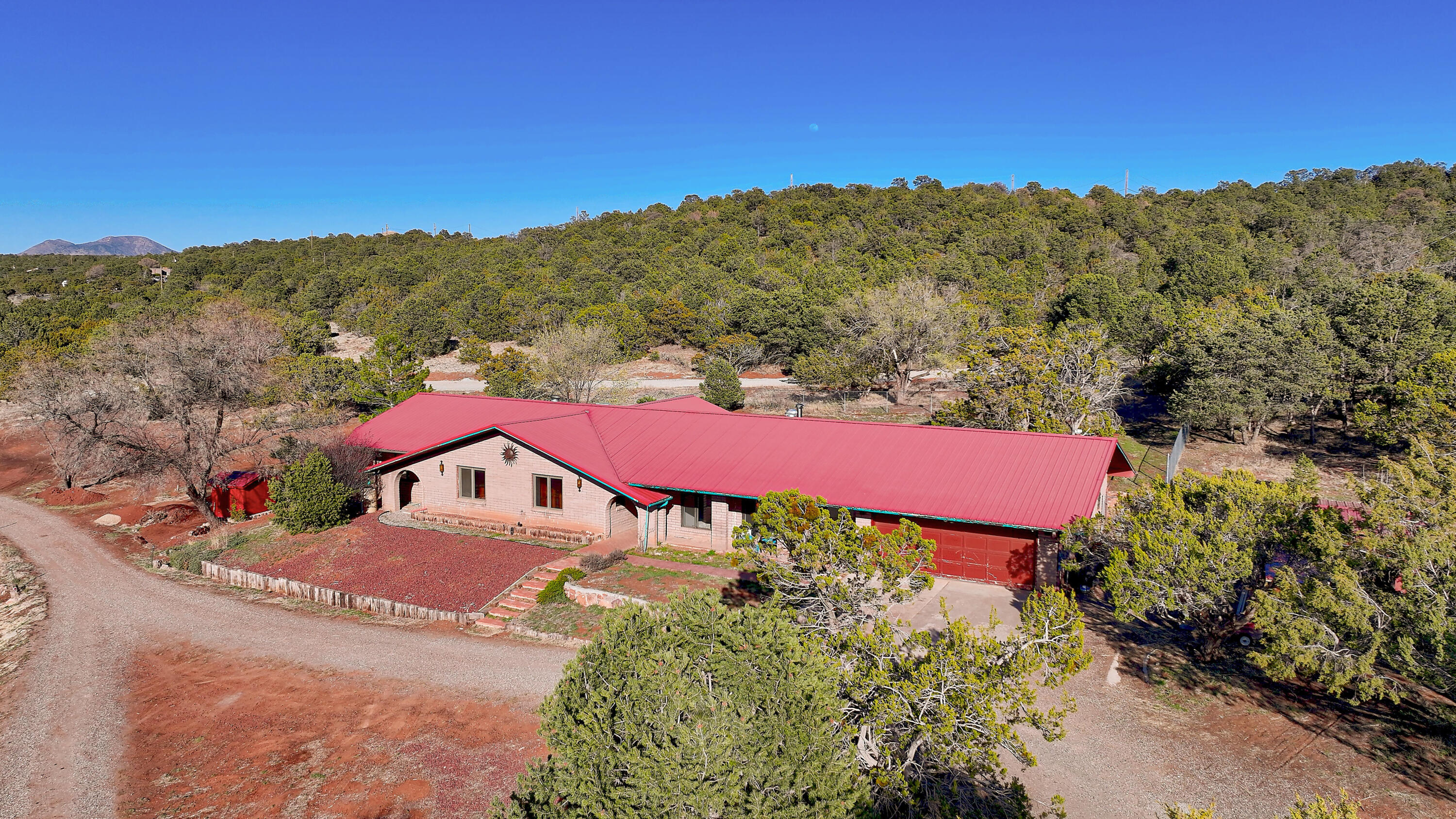 4.70 acres in Gutierrez Canyon, close in and an easy commute to ABQ. Drive into this mountain retreat to enjoy views, privacy and serenity.  The slump rock home offers plenty of space for multigenerational living.  Featuring 2 primary suites, the Guest suite and the 2nd primary offering a private sitting area. There are additional bedrooms and two offices, with many options for configuring your needs. The living room and dining area are a wall of windows with Sandia Mountain views. The cozy family room offers a wood burning stove for those chilly winter nights.  Plus hot water baseboard heat. The huge kitchen features lots of cabinets, storage and spacious countertops. Sit in the screened porch or under the covered patios to enjoy East mountain living at its finest.