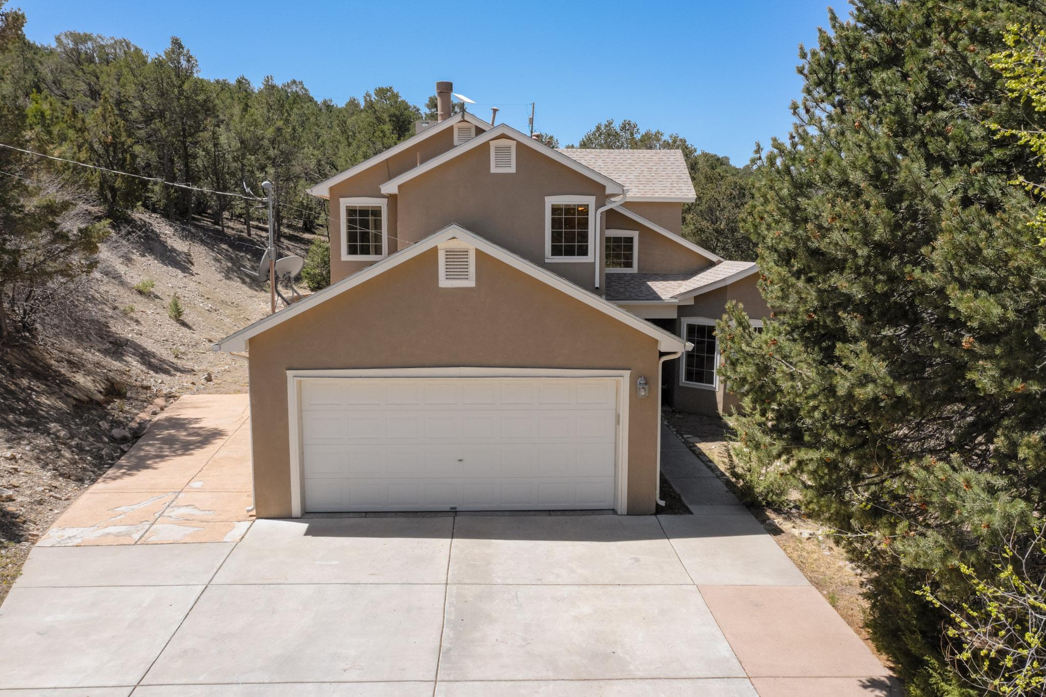 Welcome to your light-filled mountain retreat! This double-story home offers privacy, tranquility, and stunning natural surroundings. Designed to embrace its setting, the home is flooded with natural light from large windows throughout. The great room features soaring ceilings and a charming kiva fireplace, creating a warm, inviting space. Enjoy close proximity to National Forest hiking and biking trails for outdoor adventure right out your door. The primary suite offers a peaceful escape with two closets, its own fireplace, and treetop views. The layout includes two driveway access points for convenience, and the oversized garage features an additional bay perfect for a utility vehicle or workshop. A New septic was installed in 2021. Home is on a shared well with 10 other homeowners.