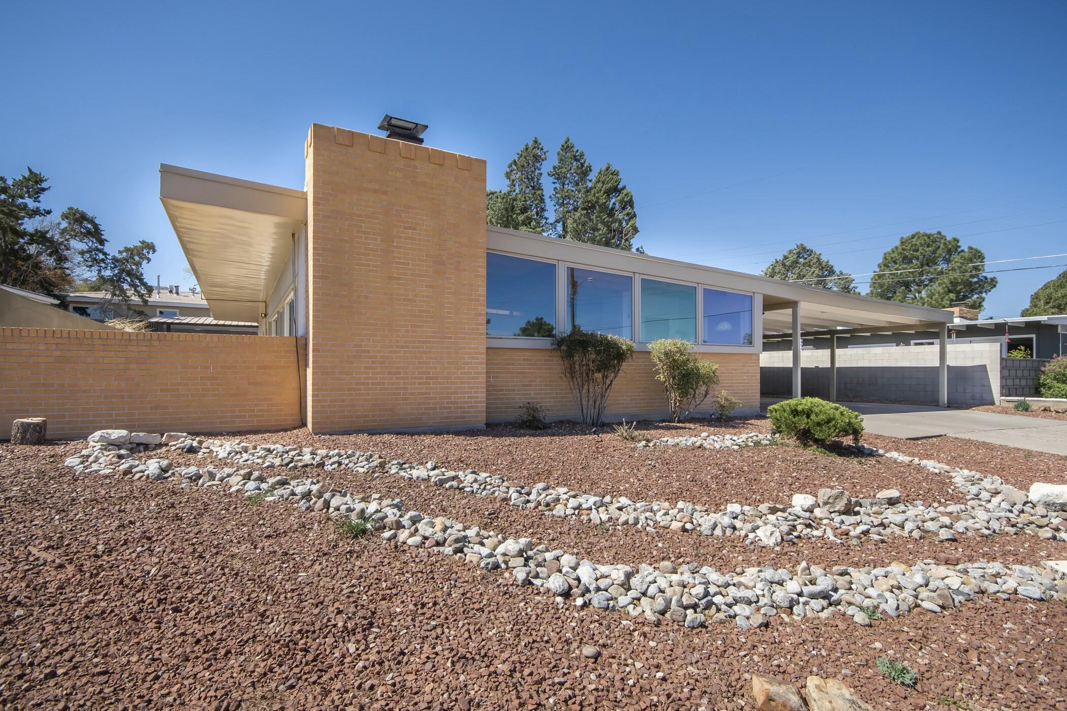 Discover this beautifully maintained mid-century residence nestled in the desirable Sandia Ridge neighborhood, just moments from Altura Park. This home features expansive windows that showcase breathtaking views of the Sandia Mountains, filling the interior with natural light. Floor-to-ceiling sliding glass doors seamlessly connect the living spaces to the outdoors, perfect for indoor-outdoor living and entertaining. The open-concept kitchen and dining area boasts wood-beamed ceilings, stained concrete floors, and modern updates in the kitchen and bathrooms, blending classic charm with contemporary amenities. The home offers three bedrooms and two bathrooms, providing comfortable space for family and guests.
