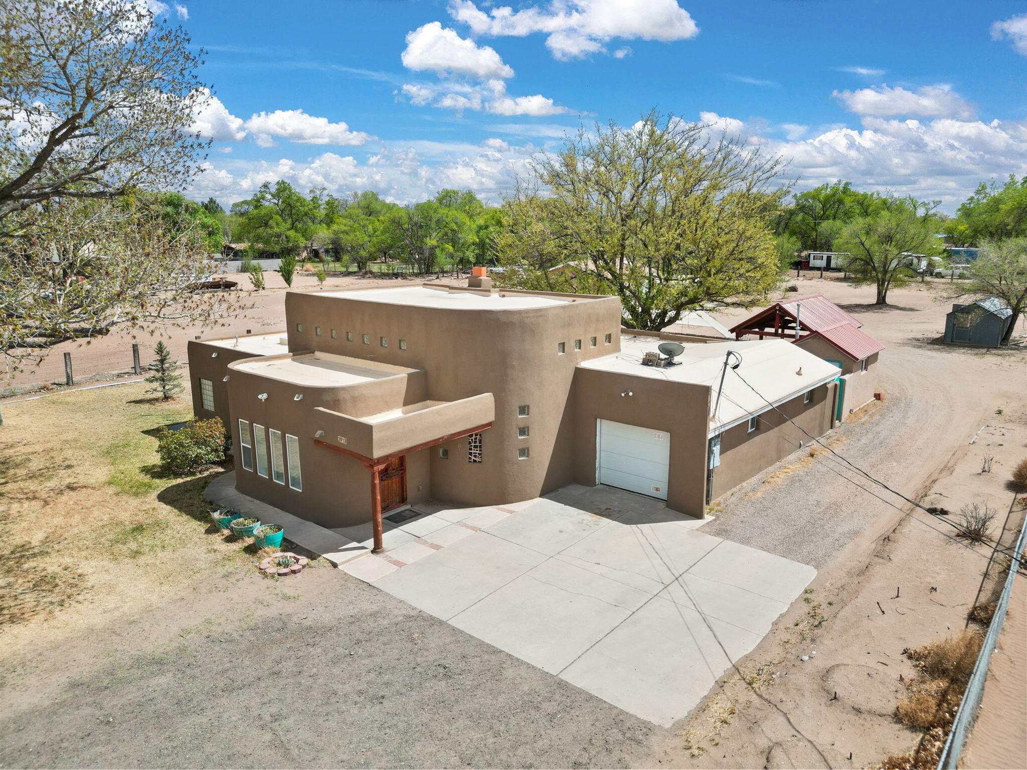 Welcome to this charming Pueblo style ranch home in the heart of the South Valley! Nestled on 1.2 acres, this spacious and versatile property offers 2 bedrooms with the potential for a third, 2 bathrooms, a 3 car garage, and 3 generously sized living areas--ideal for flexible living, entertaining, or multigenerational use. Step inside to soaring 16-foot ceilings, 3 cozy fireplaces, and thoughtful details throughout. The primary suite offers a peaceful retreat with a jetted tub, walk-in shower, and walk-in closet. Updates include stucco (2024) and freshly painted throughout the home (April 2025). The fully fenced lot is perfect for livestock and features a private well for irrigation, a steel chicken coop, two storage sheds (one with electricity), and a large finished detached garage/